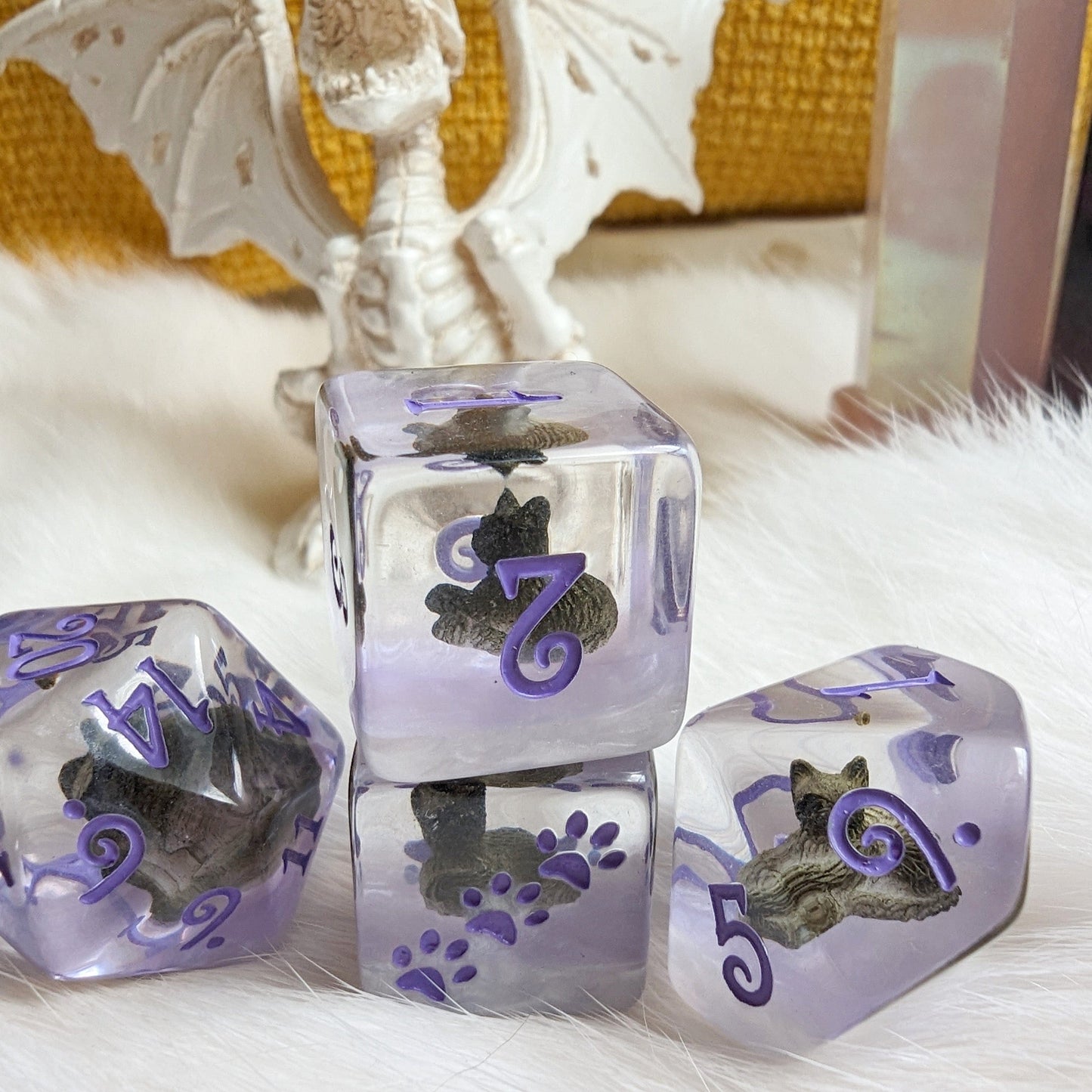 Sleepy Cat Dice Set featuring miniature resting cats inside clear resin with purple numbers for tabletop games like Dungeons and Dragons.