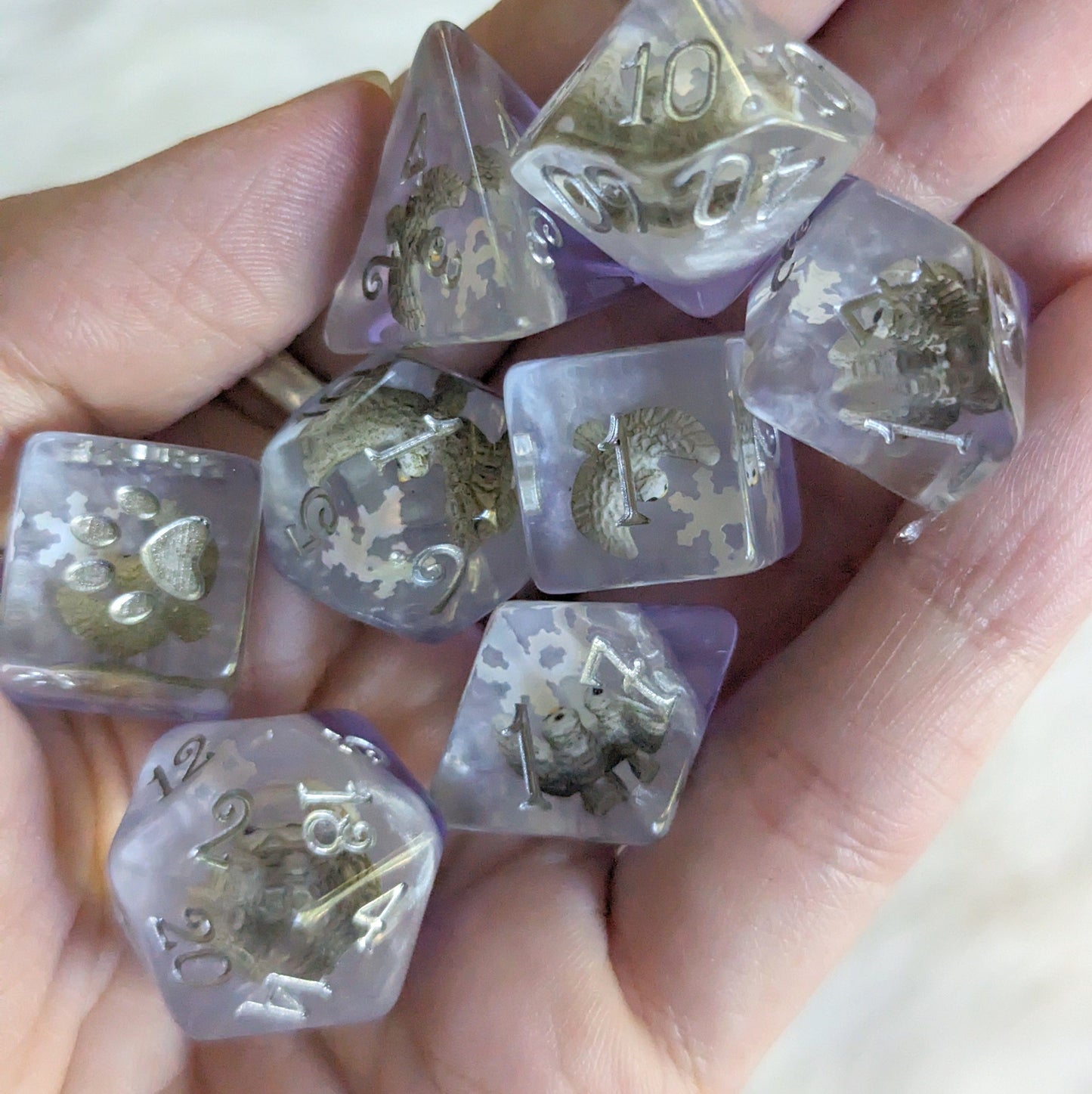 Hand holding Snowy Owl Dice Set with miniature flying owls and paw counters, ideal for Dungeons and Dragons and TTRPGs.