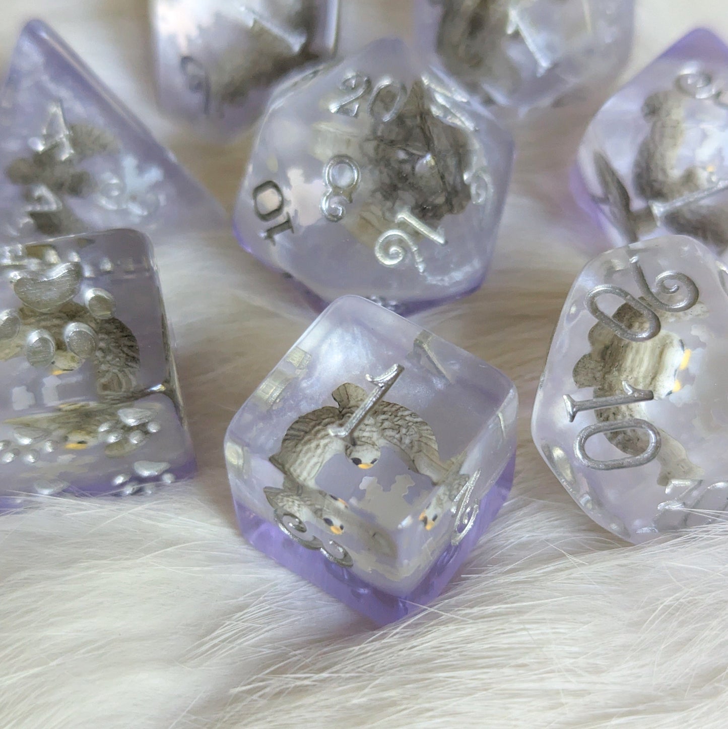 Snowy Owl Dice Set with miniature owls in clear resin, silver and purple layers, custom font, 8 polyhedral dice for TTRPGs.