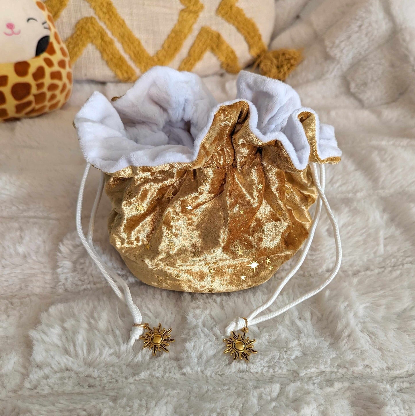 Luxurious gold velvet dice bag with starry design, soft white plush lining, and elegant cord drawstrings adorned with sun charms.