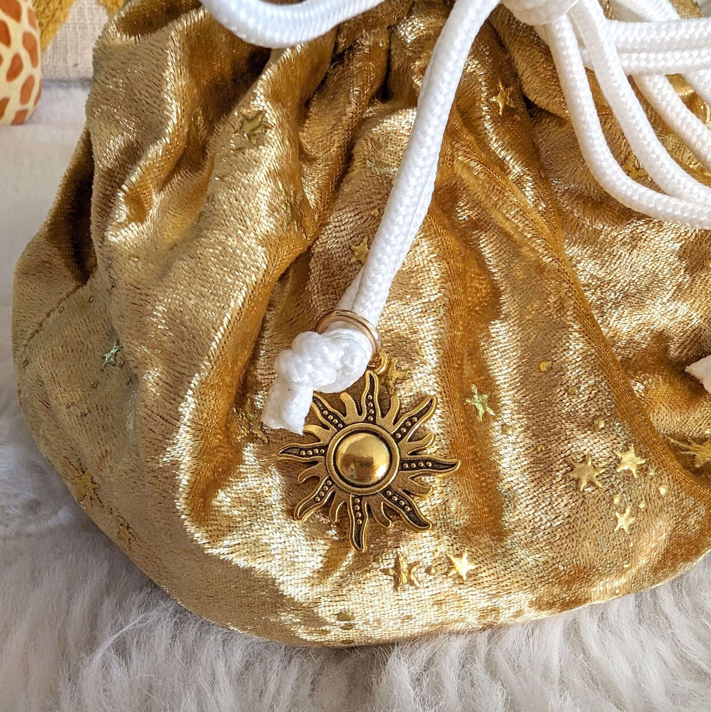 Gold velvet dice bag with sun charm, featuring white drawstrings and star designs.