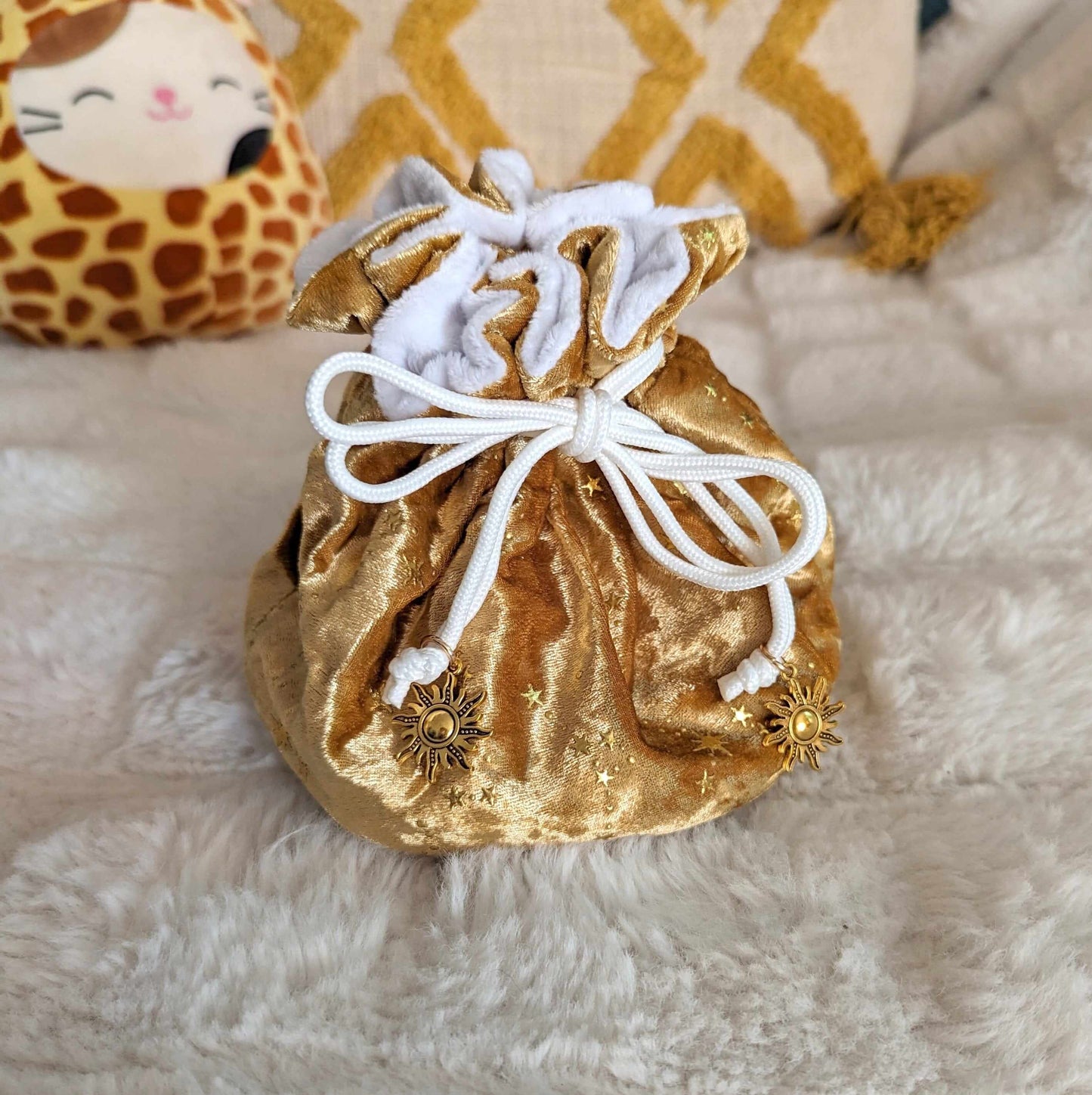 Gold velvet dice bag with white drawstrings and sun charms, featuring a starry pattern.