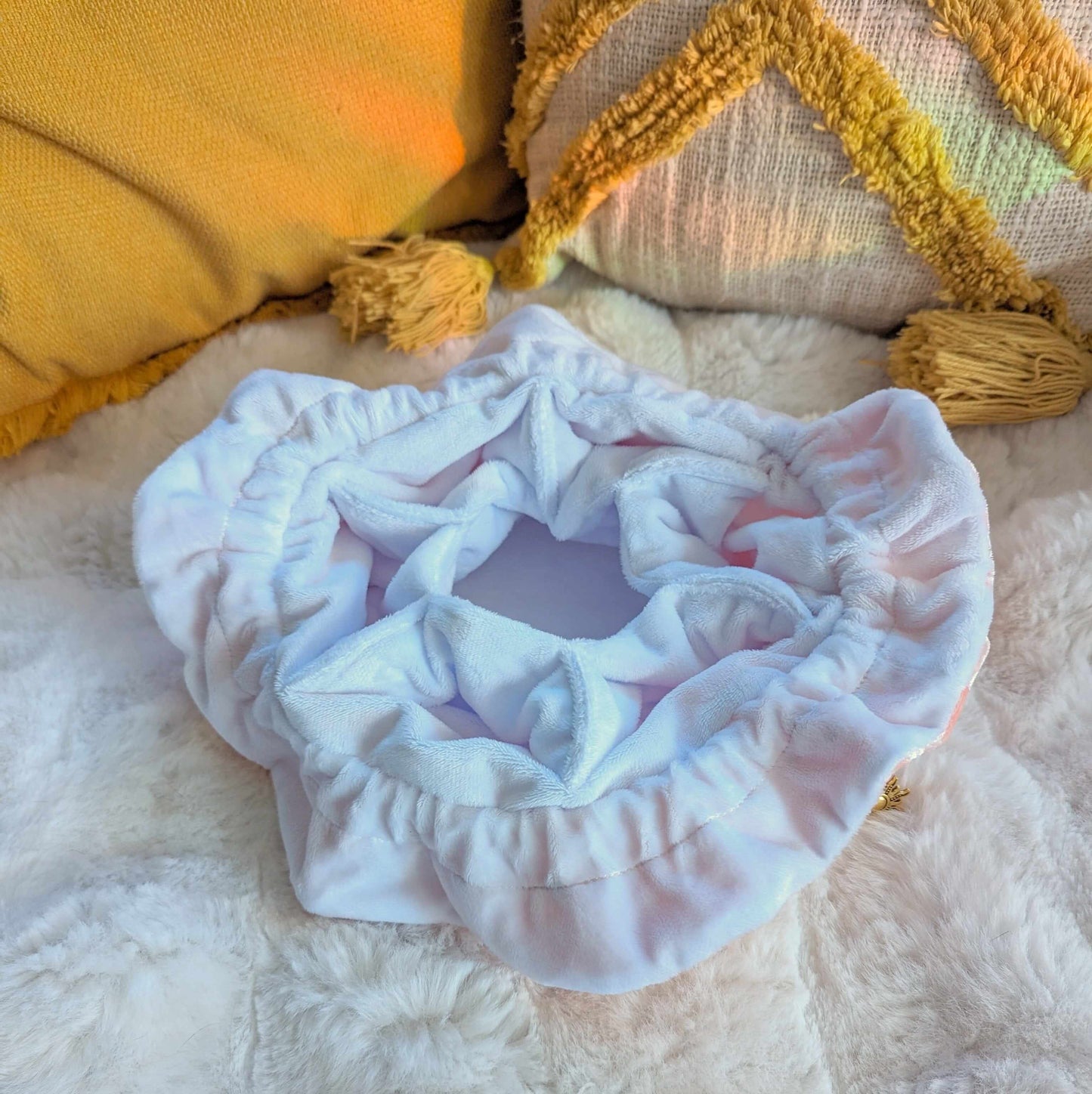 Open starry pink dice bag with multi pockets, made of soft velvety fabric and gold star accents, resting on a cozy blanket.