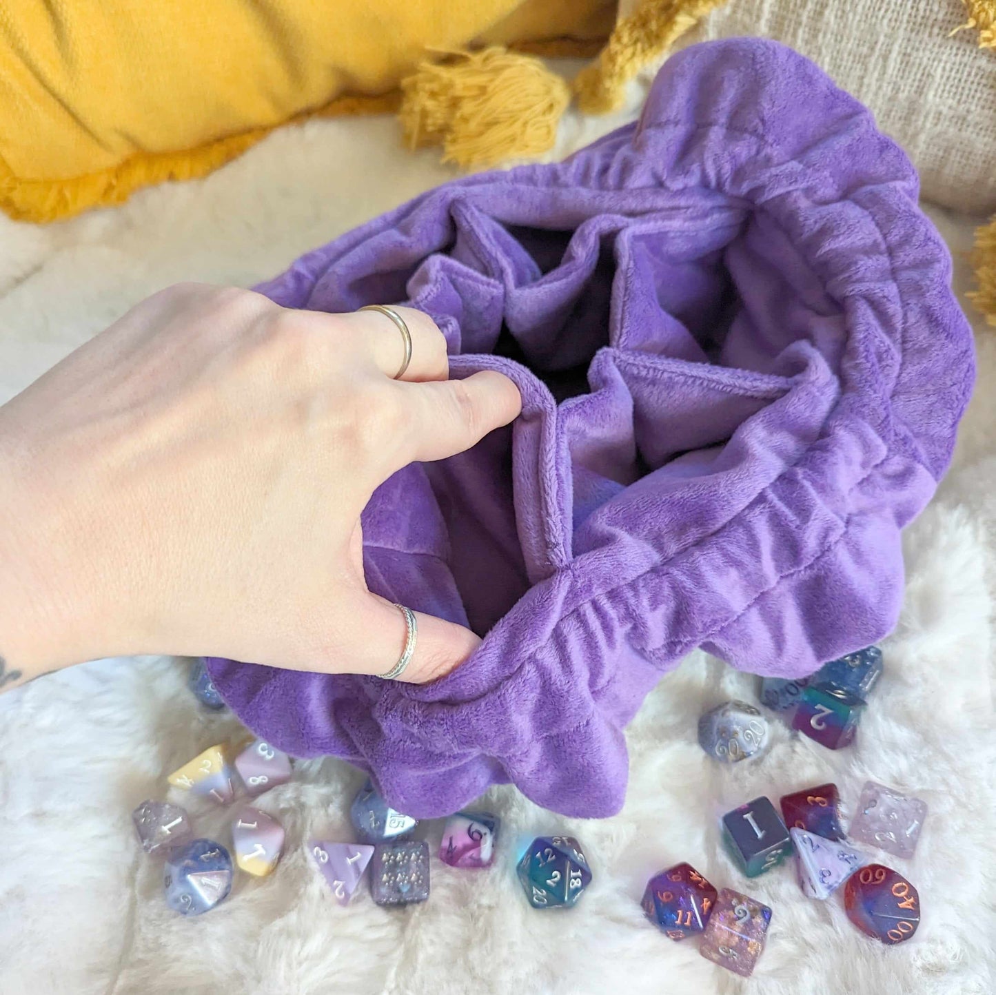 Purple wizard dice bag with multi pockets and scattered dice, showing plush velvet fabric and spacious inner compartments.