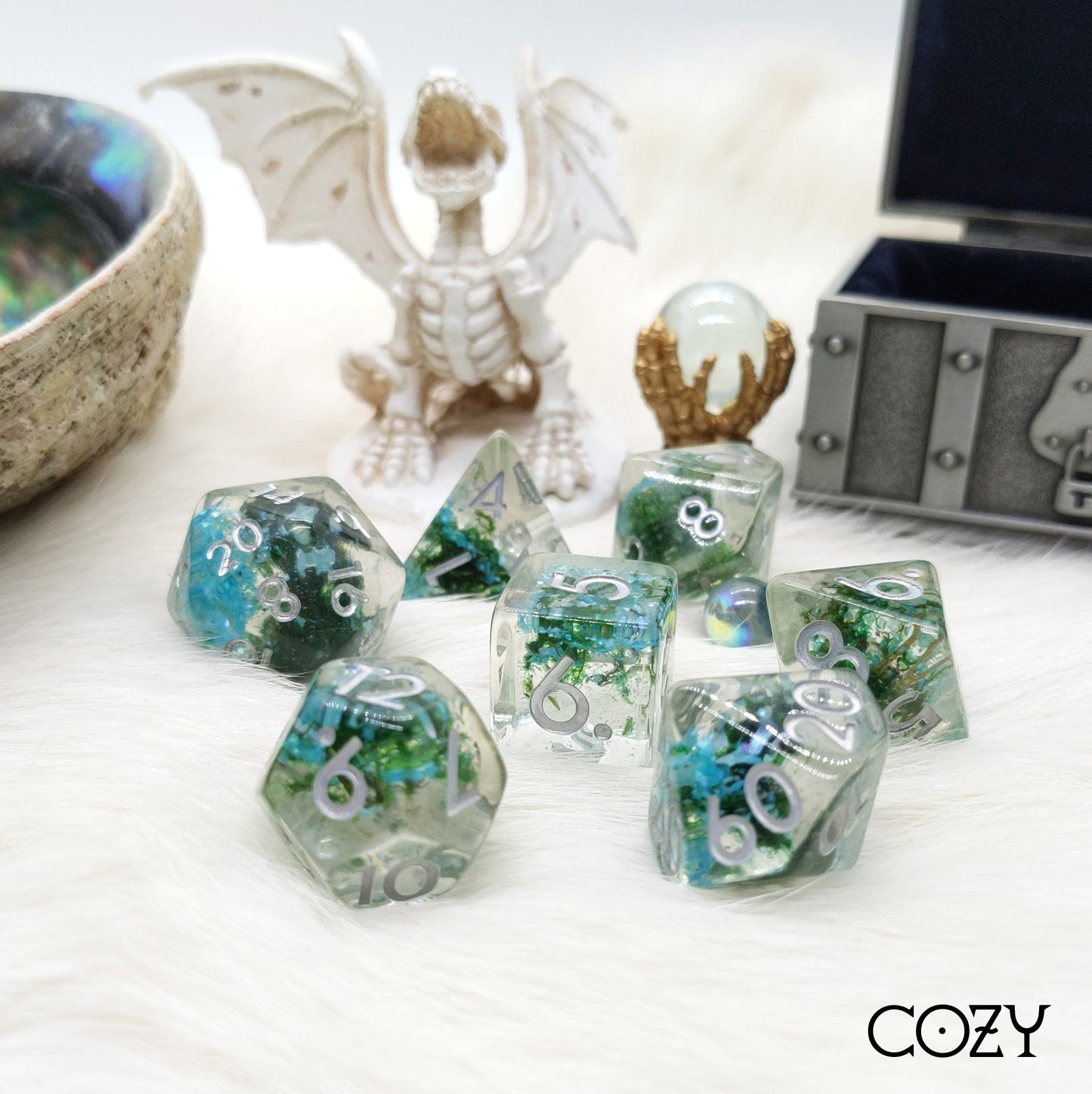 Abalone shell and moss TTRPG dice set with clear resin, featuring a dragon figurine and treasure chest in the background.