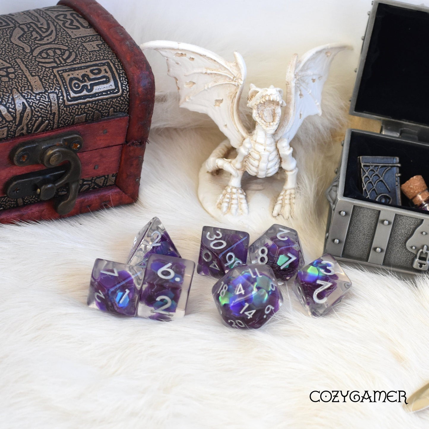 Amethyst Glint Dice Set with iridescent glitter, displayed on fur with treasure chest and dragon figurine. Perfect for tabletop games.