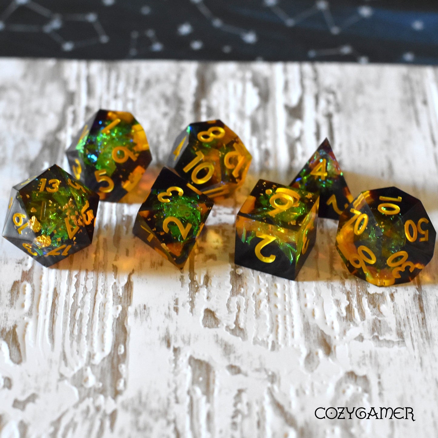 Autumn Magic sharp edge resin dice set, 7-piece black and yellow polyhedral TTRPG dice, with glitter, on a textured surface.