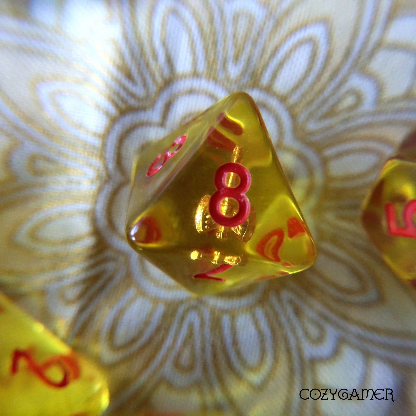Yellow polyhedral die with red numbers from the Barbarian's Axe Dice Set for tabletop RPGs, displayed on patterned background.