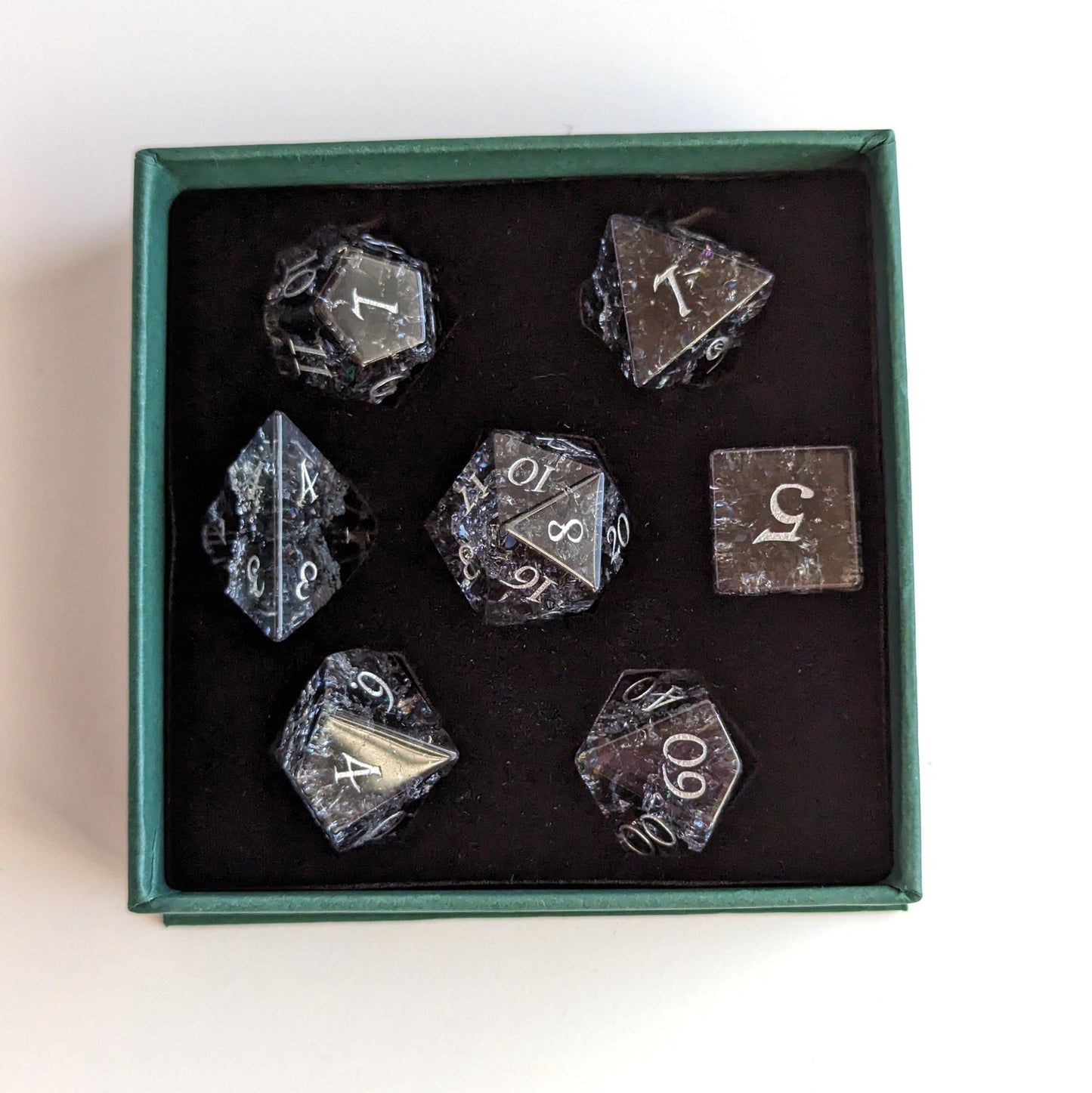 Black and blue crackled glass dice set in a box, including a DnD standard 7-piece set with carved numbers, perfect for gaming.