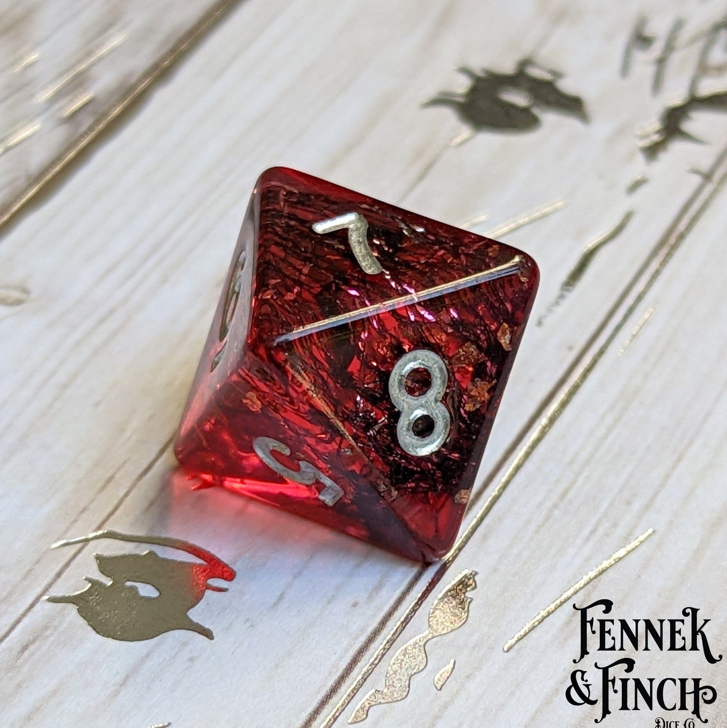 Red Blood Skies 20-sided dice with tiny bat design from dark forest themed dice set by Fennek & Finch on wood surface.