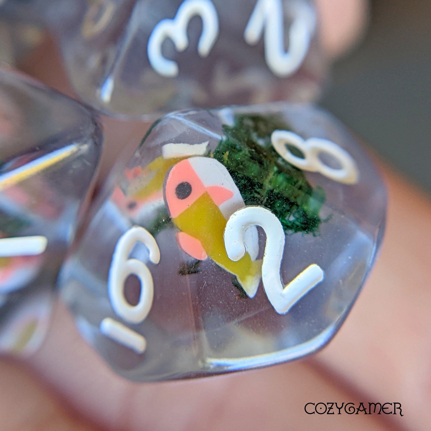 Blue Swimming Fish DnD Dice with cute fish and real dried moss inside clear resin for tabletop games like Dungeons and Dragons.
