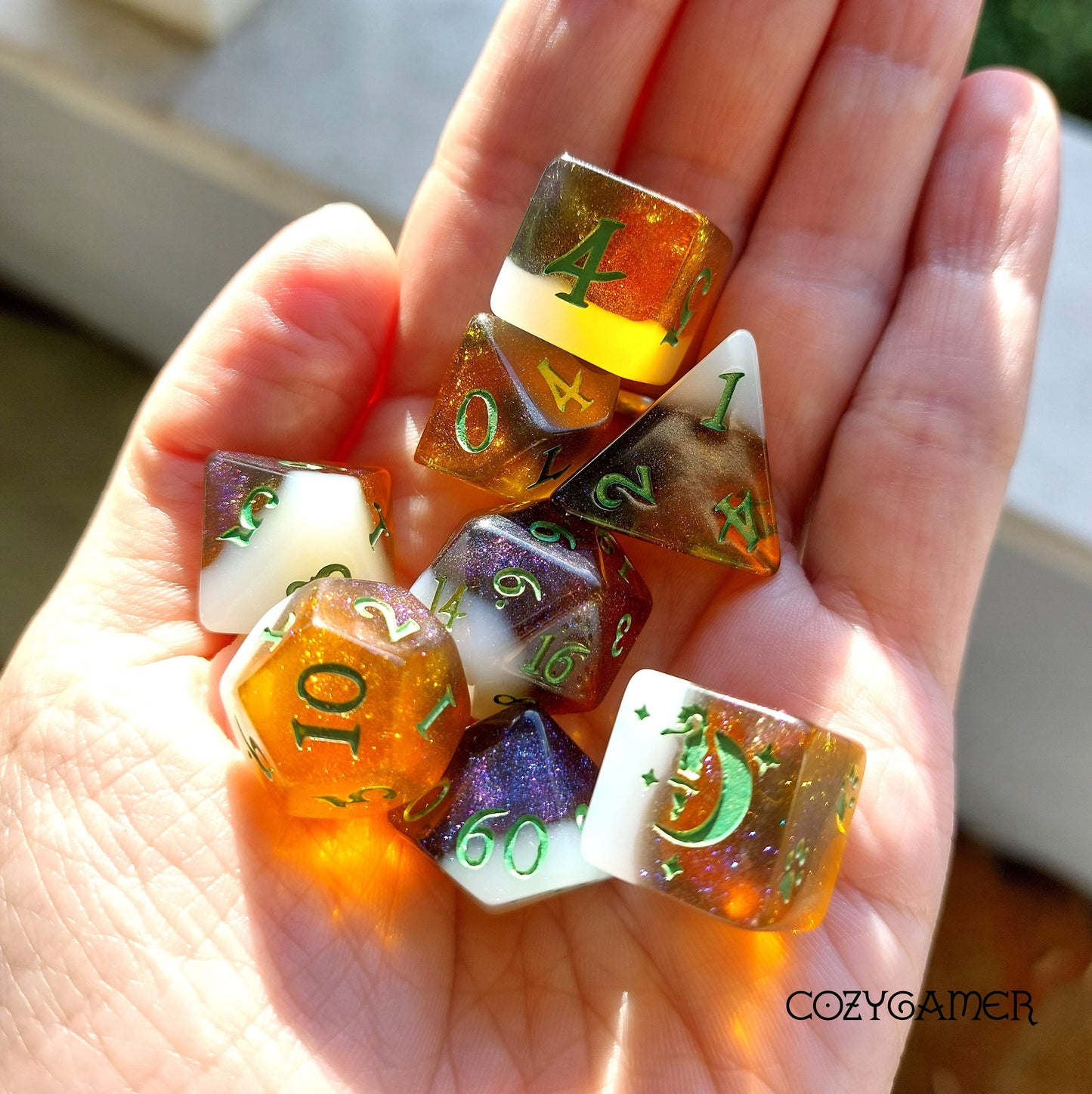 Hand holding Calico Hazy IPA Dice Set with beer-themed DND dice in cat colors, including D20, D12, and unique designs.