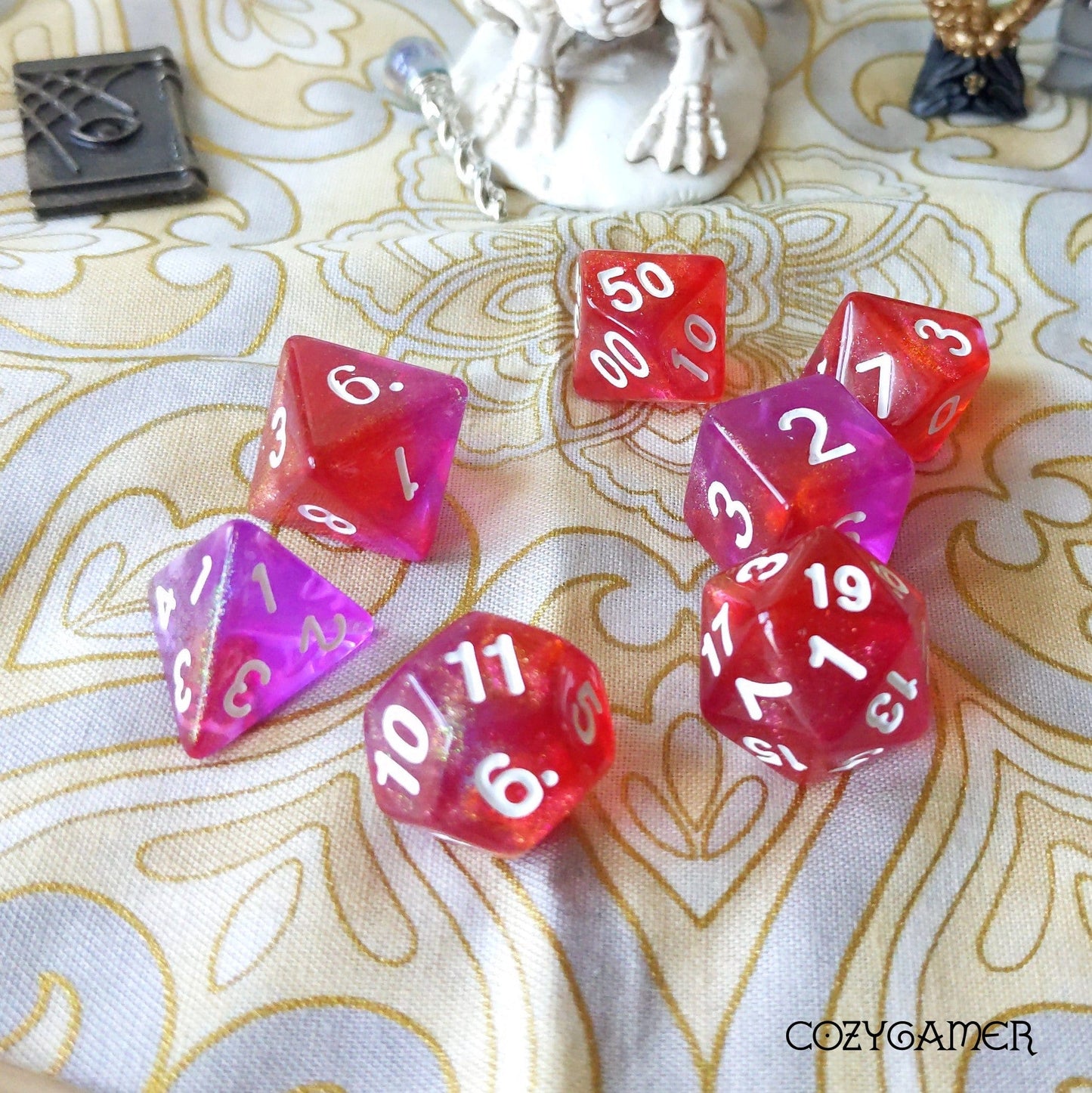 Red and purple polyhedral RPG dice set on decorative fabric surface, ideal for tabletop games like Dungeons and Dragons.