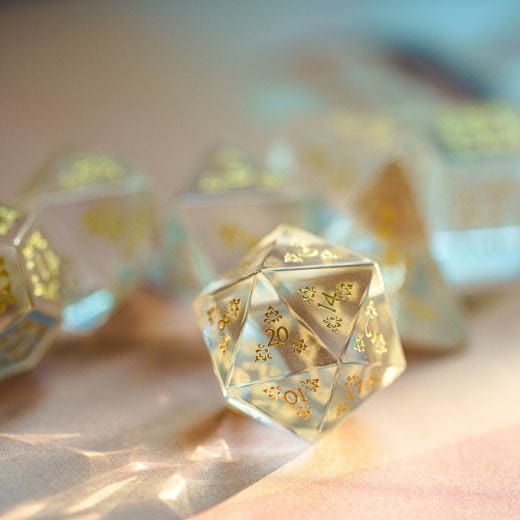 Semi-precious gemstone carved glass dice set with gold details for TTRPG, displayed in soft lighting.
