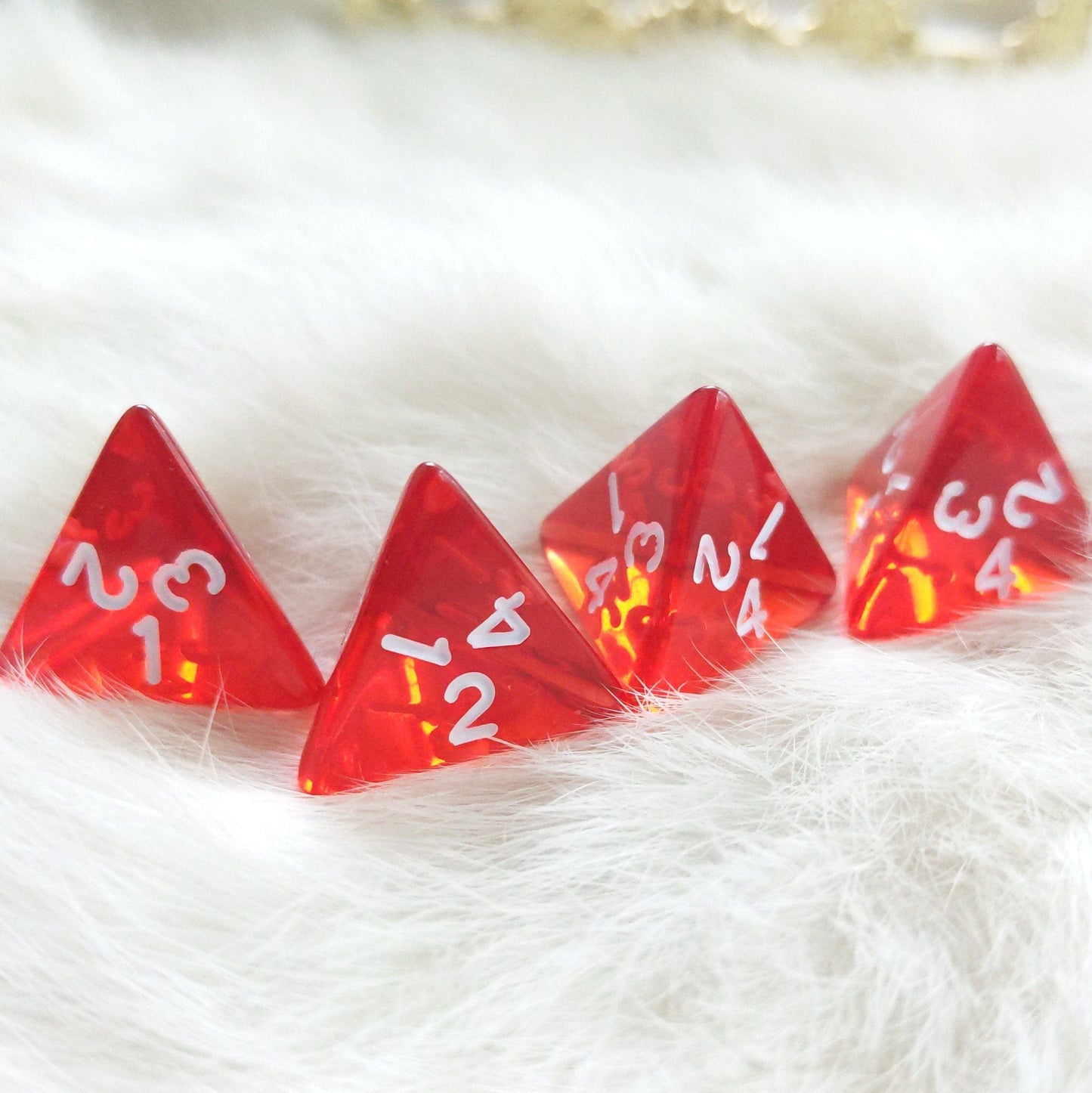 Clear red D4 dice set of 4 for making healing potions in Dungeons and Dragons, placed on a soft white surface.