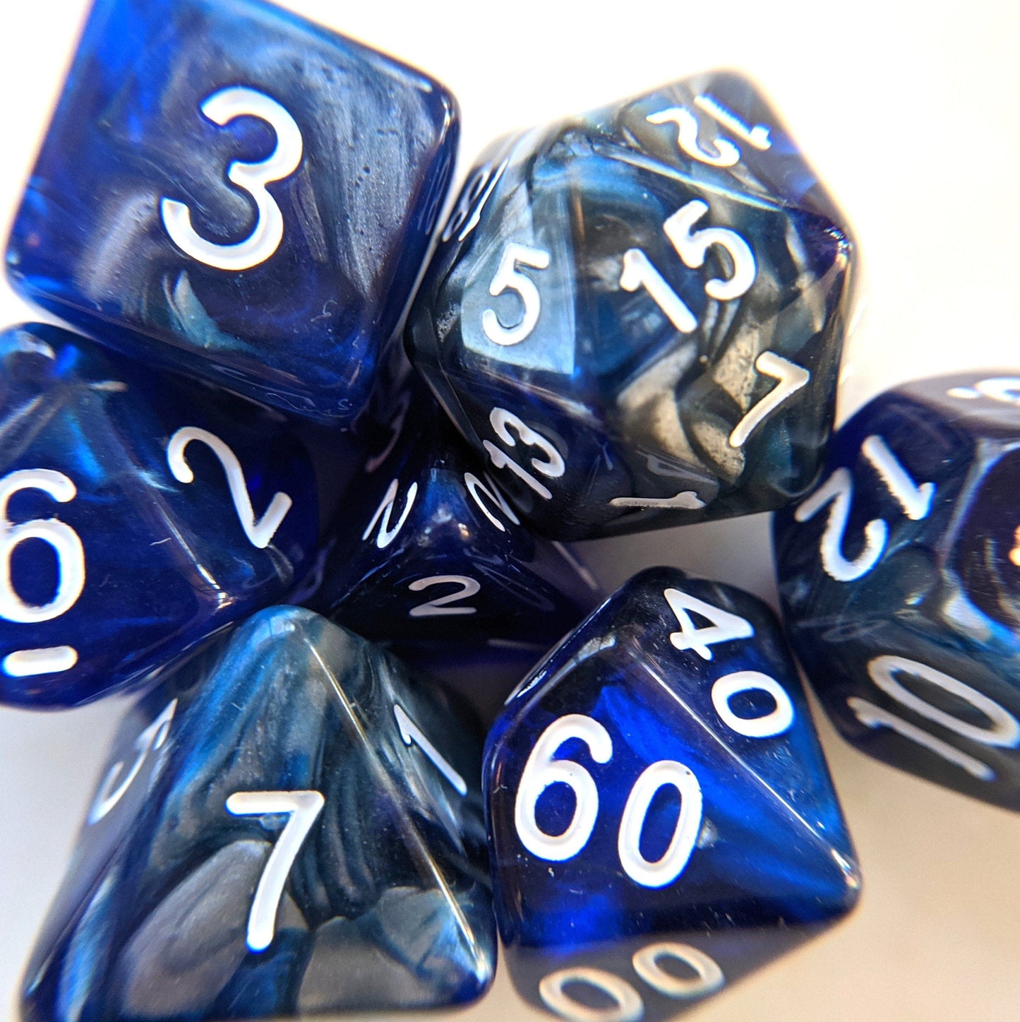 Blue and silver marbled polyhedral dice set for Dungeons and Dragons, featuring numbers in white on acrylic material.