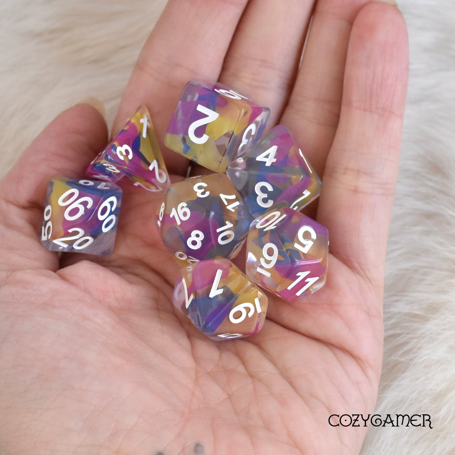 Color Spray Dice Set with colorful shavings, 7 polyhedral dice for Dungeons and Dragons, held in a hand.