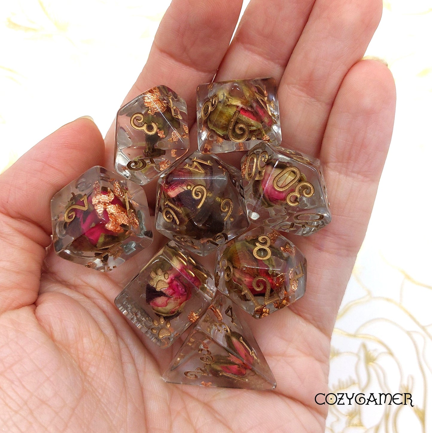 Hand holding Copper and Rose Buds Dice Set with real dried roses, clear resin, copper foil, and bronze font for DND tabletop gaming.