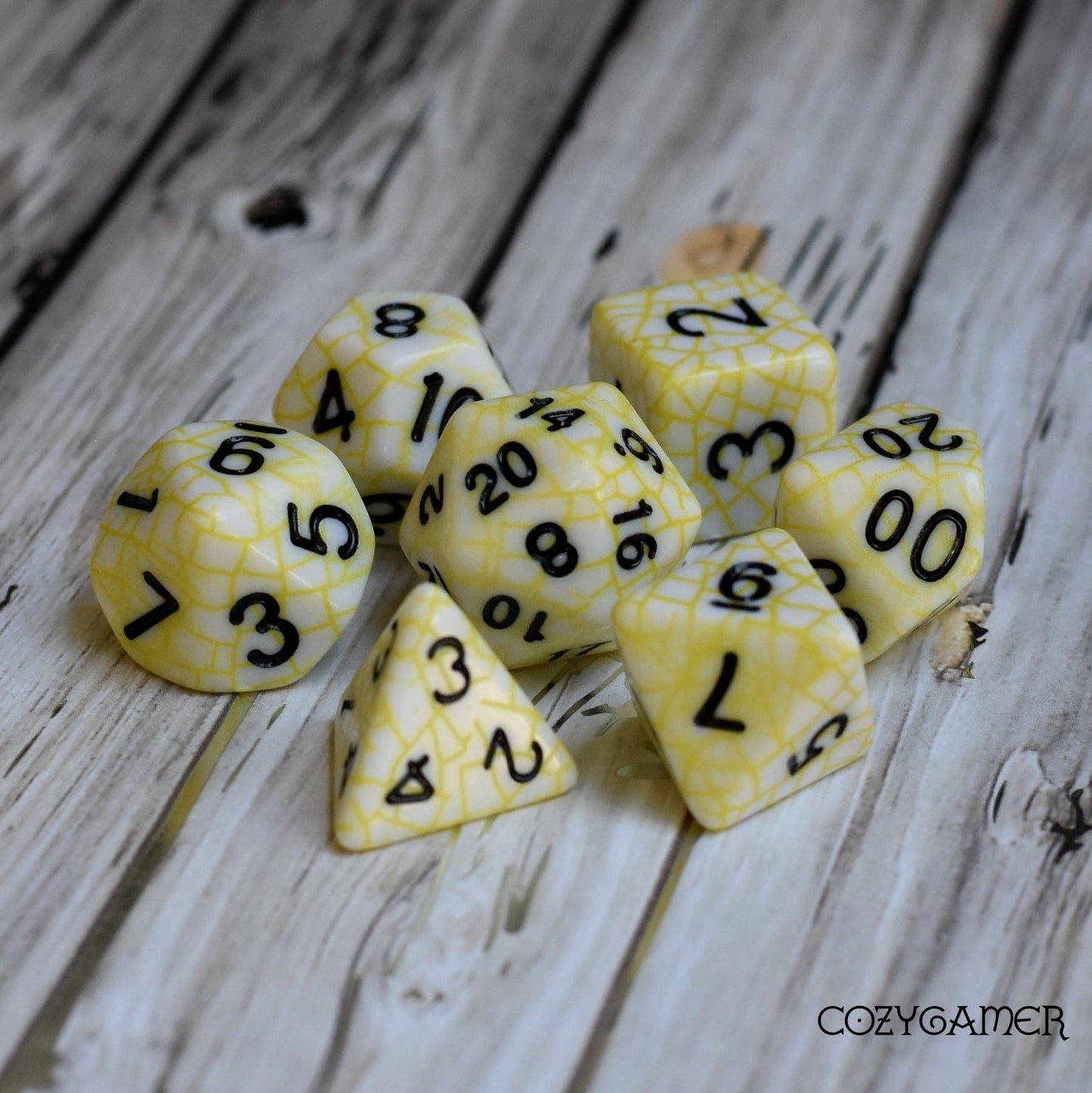 Cracked porcelain DnD dice set, white with yellow web pattern, 7-piece polyhedral resin dice for tabletop role-playing games.