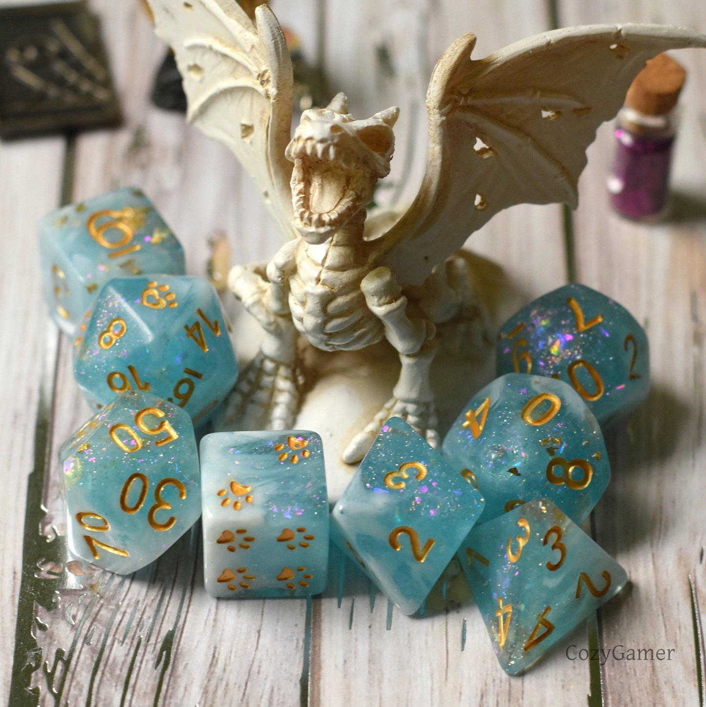 Cresting Wave DnD Dice Set with glitter resin encircling a dragon figurine, featuring custom cat wizard designs and paw motifs.