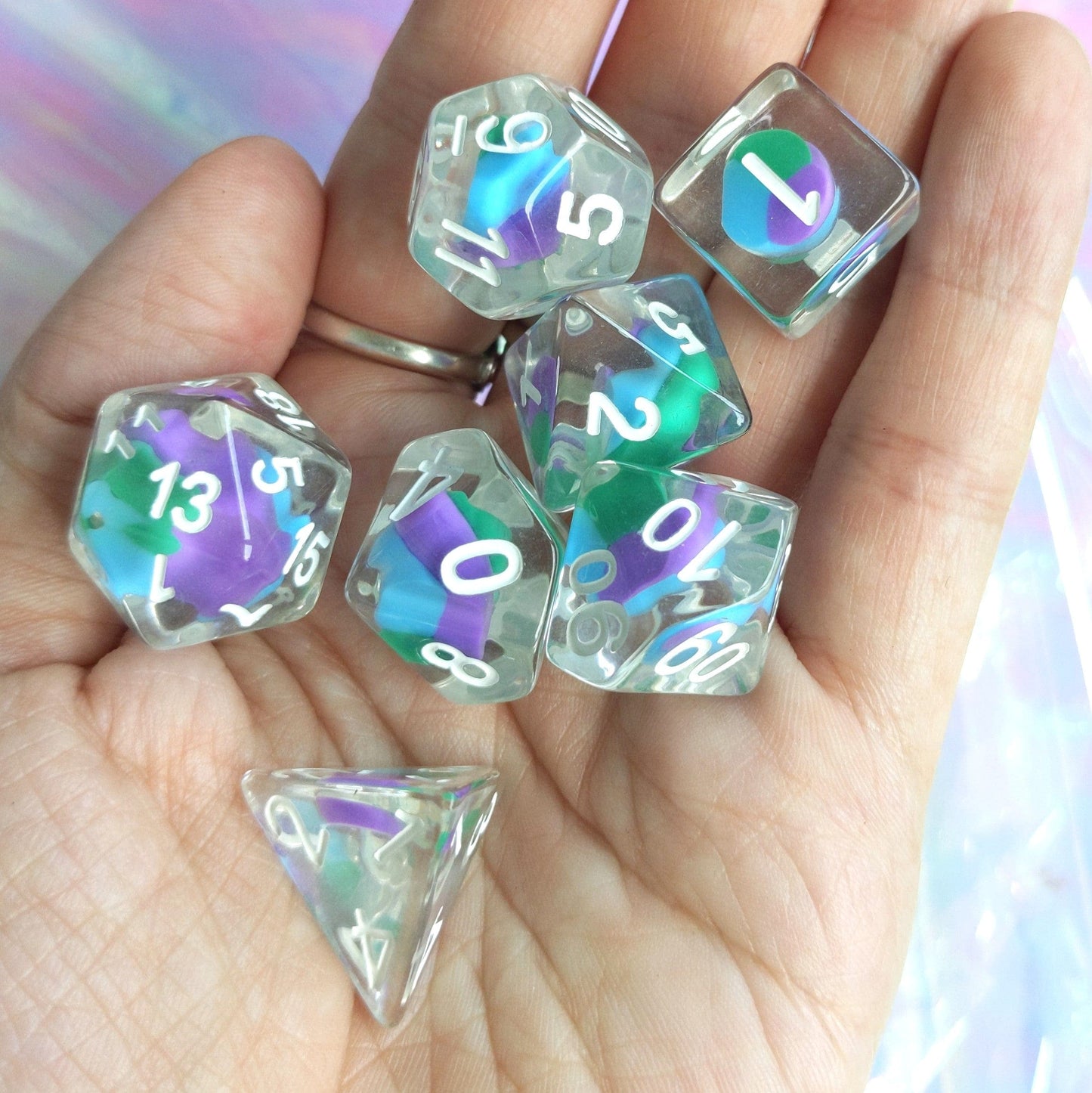 Hand holding Dragon Candy Swirl Dice Set with colorful candy centers, 7-piece polyhedral set for DnD and TTRPG gaming.
