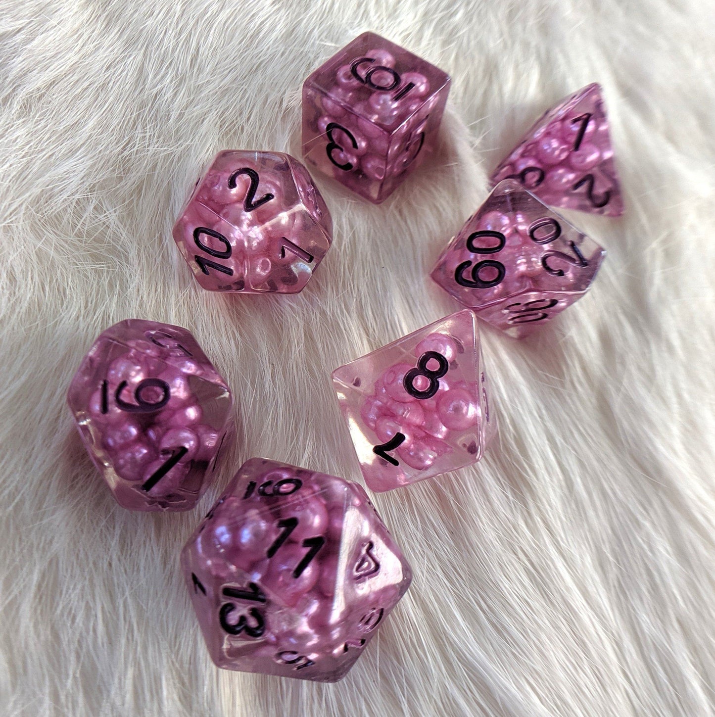 Enchantress Pearl DnD dice set with purple beads and numbers, 7 polyhedral acrylic pieces on white fur background.