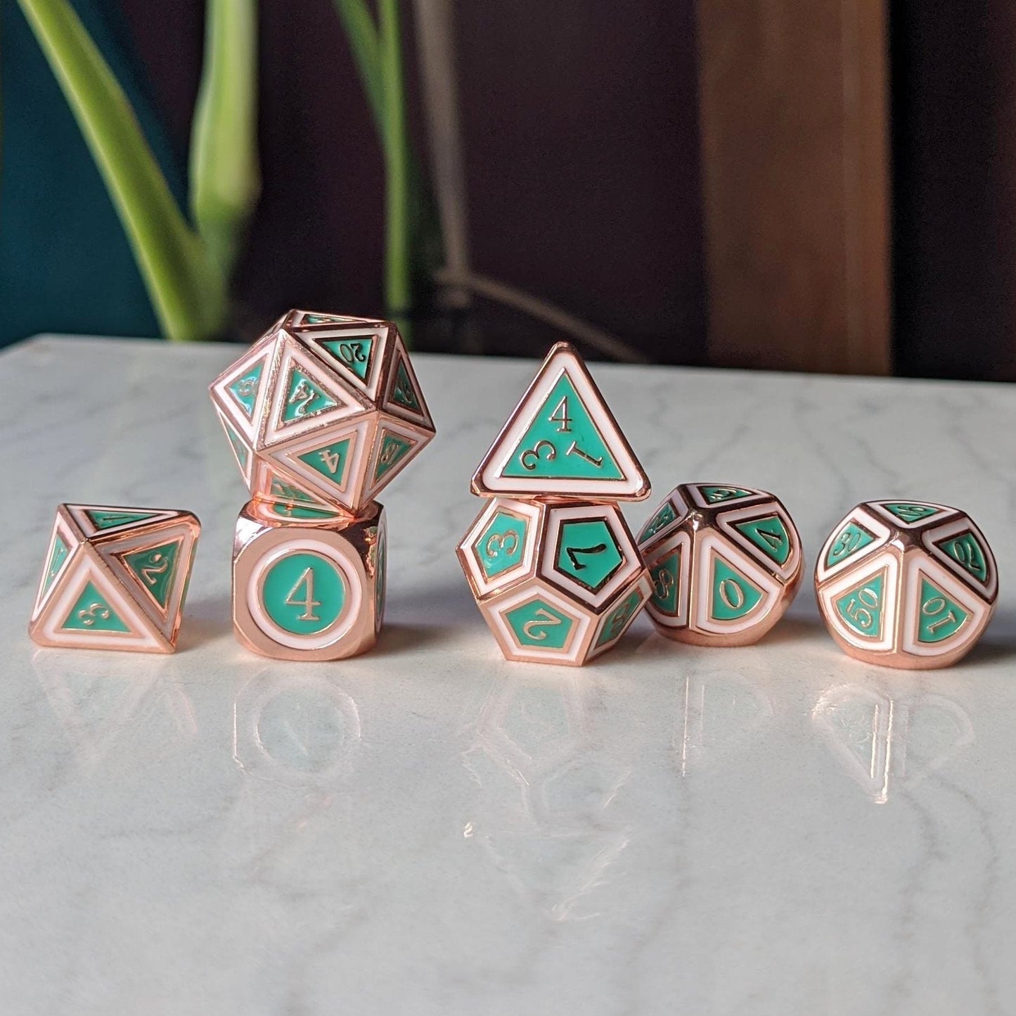 Copper plated green and white polyhedral metal dice set on a table, designed for tabletop RPG games like Dungeons and Dragons.
