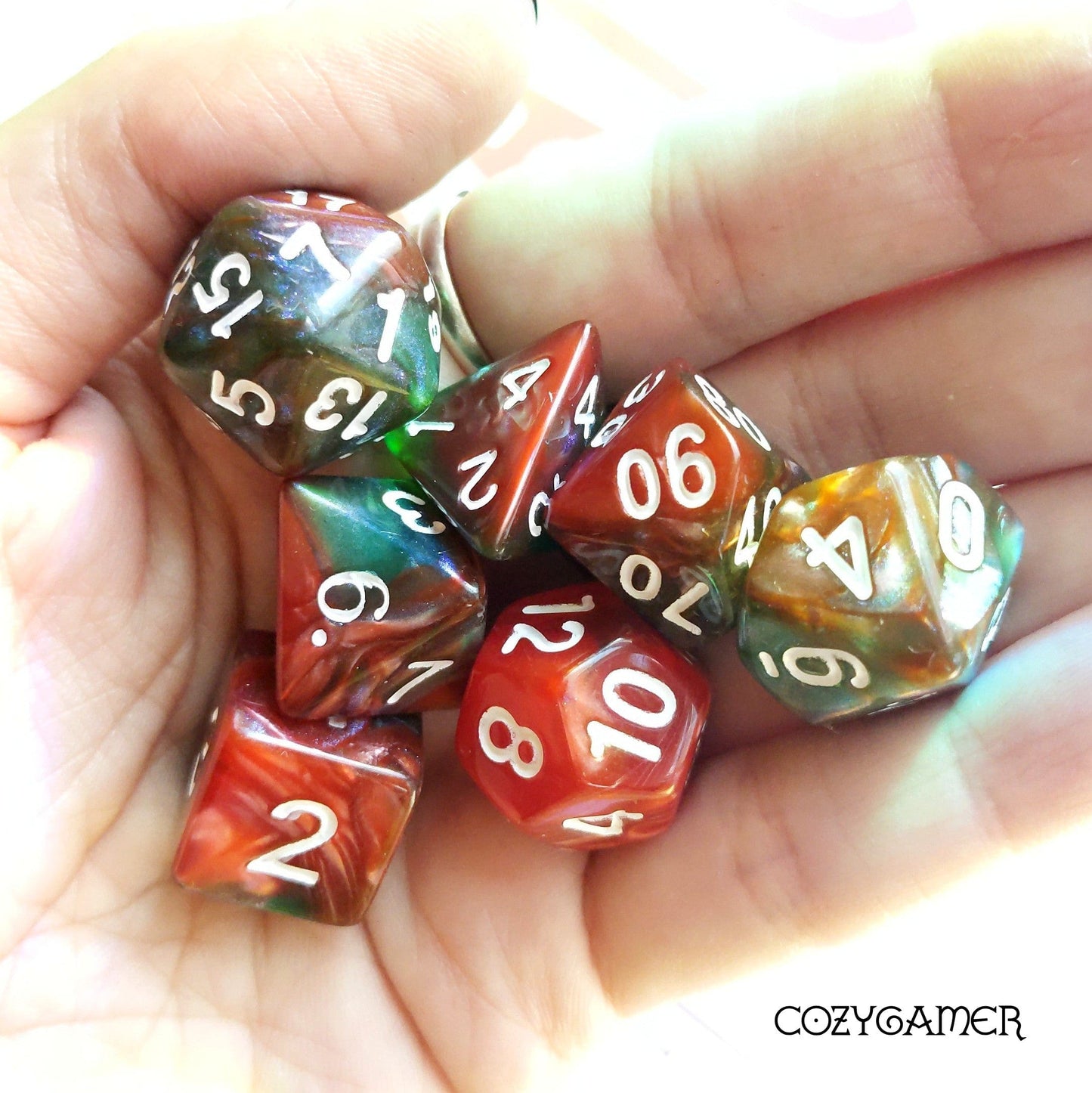 Eternal Summer Glitter Acrylic Dice Set in red and green, 7 piece polyhedral TTRPG dice for Dungeons and Dragons, held in a hand.
