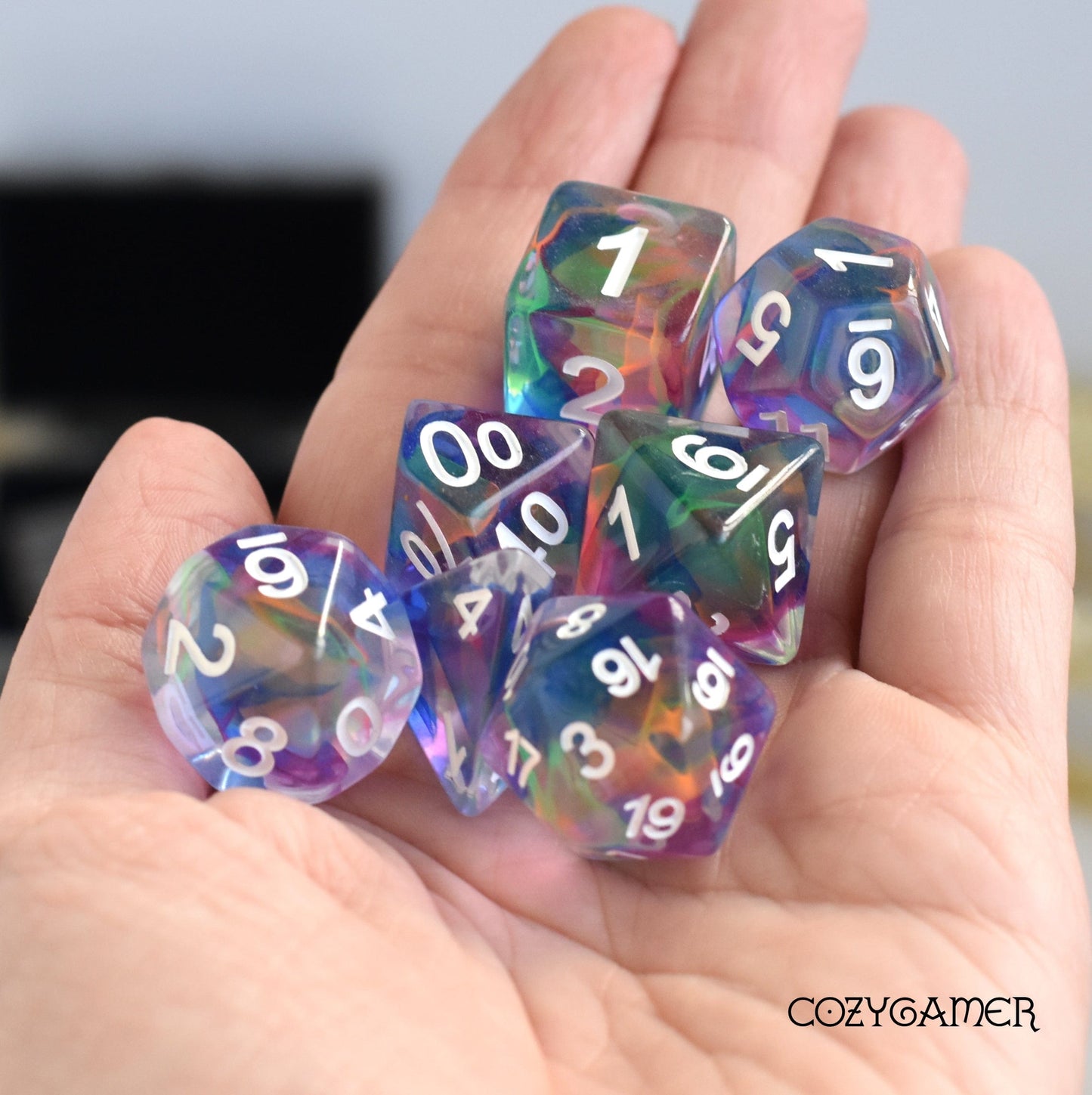 Hand holding colorful resin polyhedral dice set for tabletop games like Dungeons and Dragons.