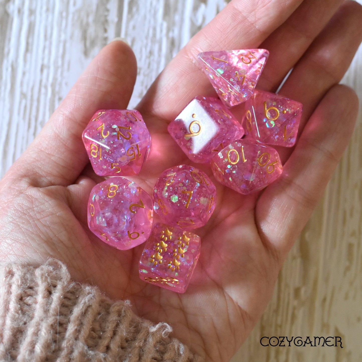 Hand holding Fairy Sparkles DnD dice set with iridescent glitter, including unique Cat Paw D6.