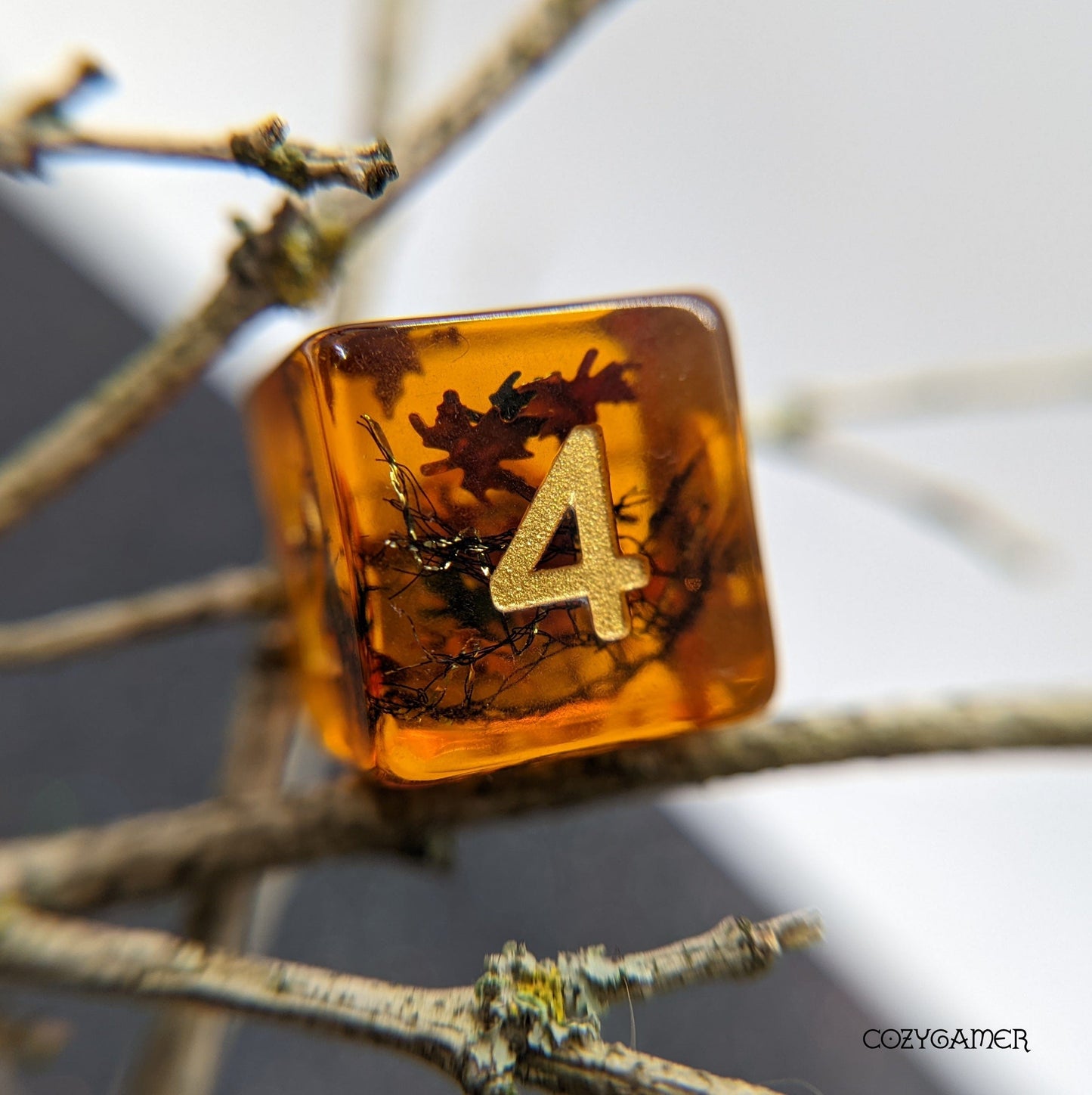 Amber resin DnD dice with leaf glitter and gold number 4, from Falling Leaves 7 Piece TTRPG set by Fennek & Finch.