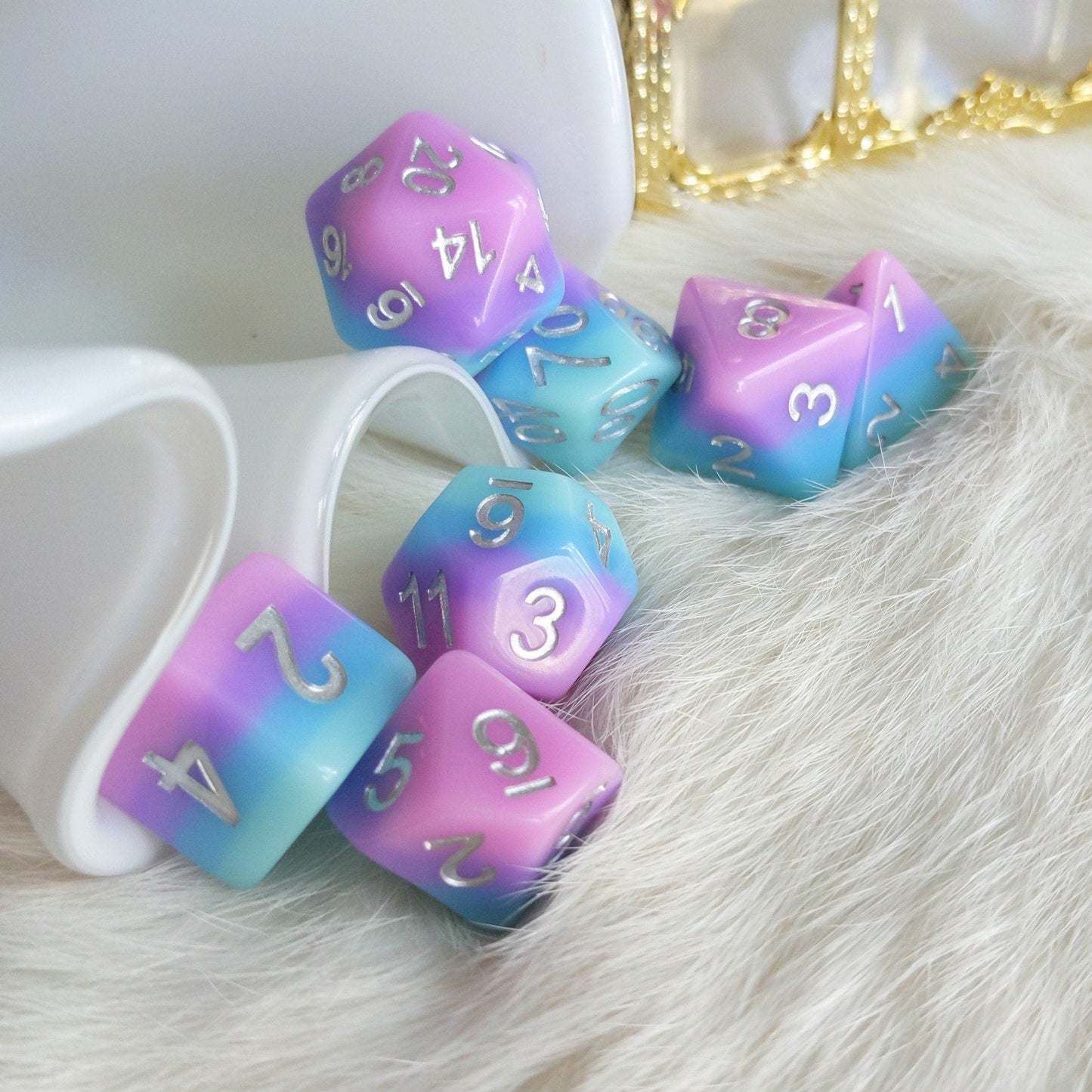 Fey Bloom Dice Set with pink, purple, and blue gradient, featuring silver numbers. Includes 7 polyhedral dice for tabletop RPGs.