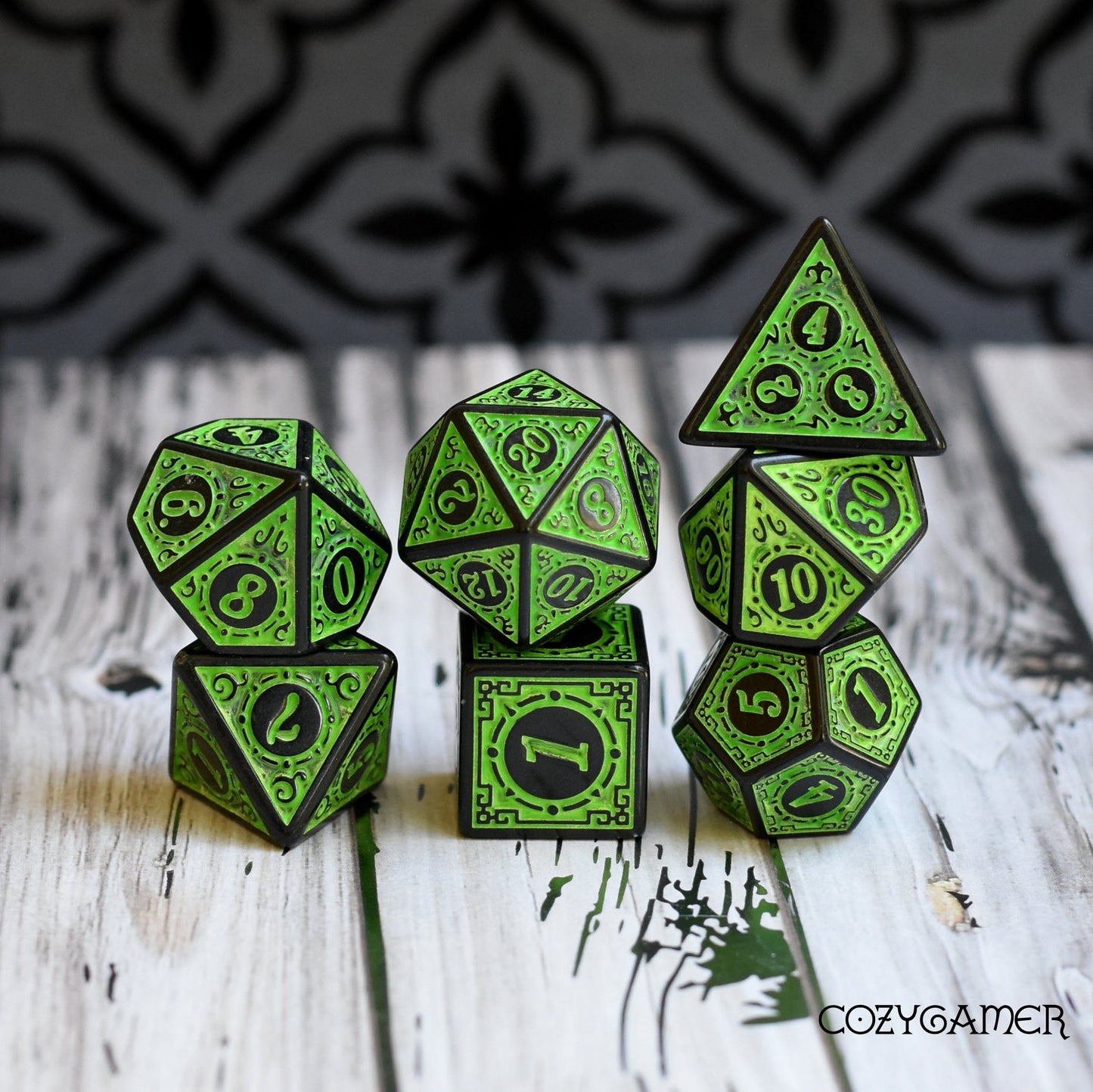 Filigree framed 7 piece green polyhedral dice set for Dungeons and Dragons and Magic The Gathering on a wooden surface.