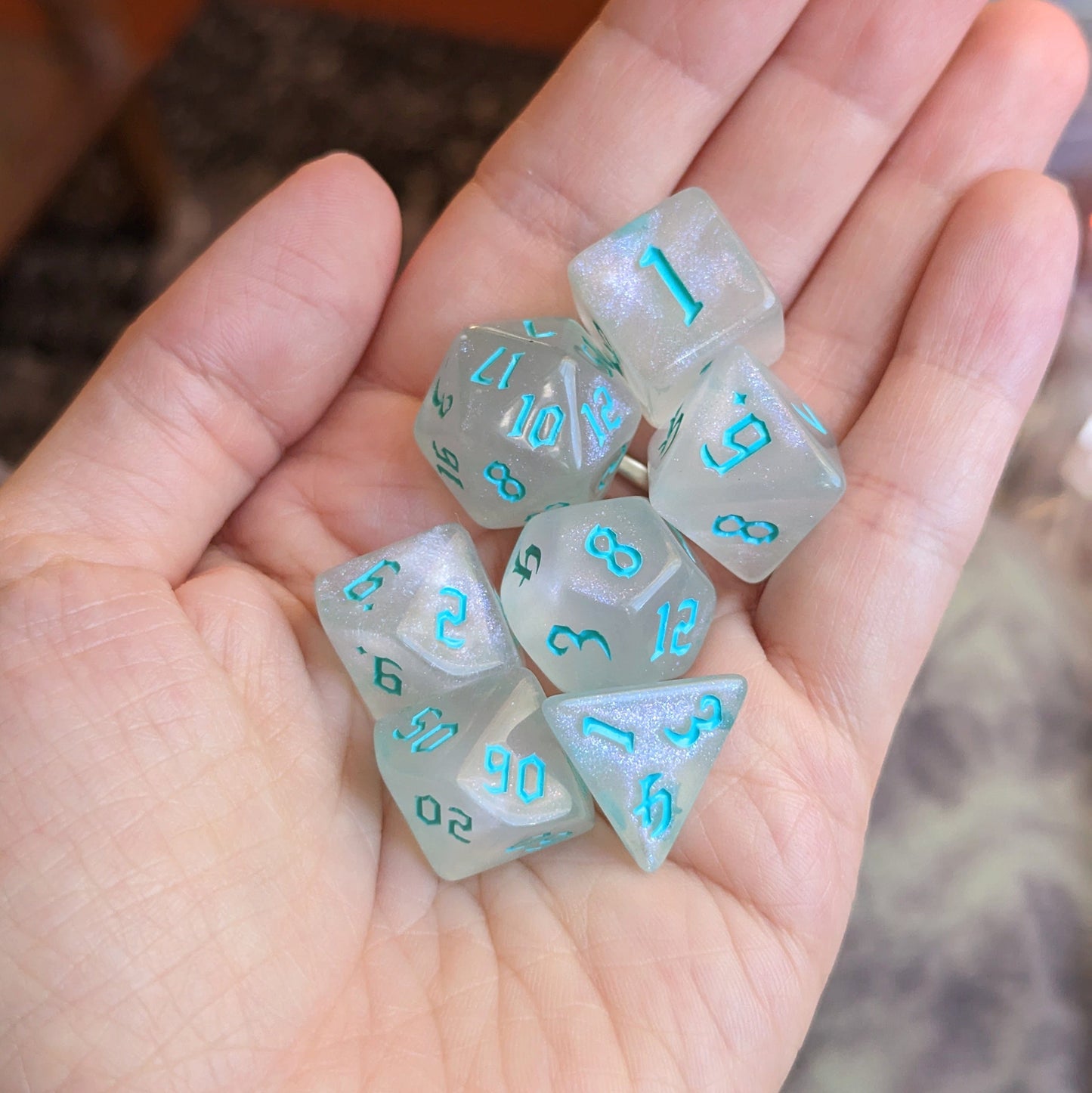 Hand holding a Frozen DND Dice Set, featuring a standard 7-piece transparent design with icy blue numbers.