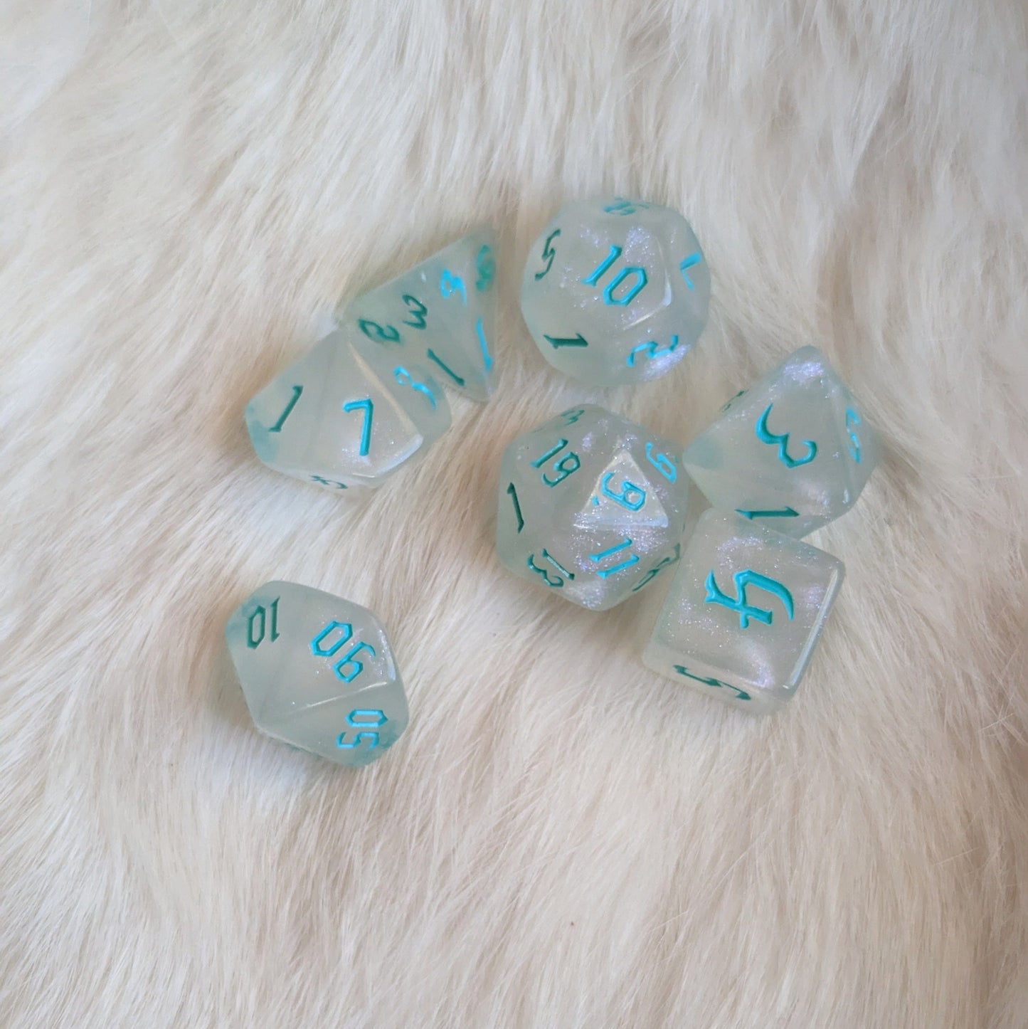 Frozen DND dice set with blue numbers, standard 7-piece RPG dice, on a soft white background.