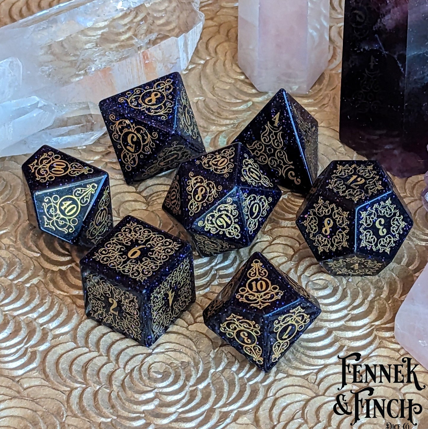 Garden Gate Blue Sandstone Gemstone Dice Set with intricate gold designs and shimmering dark blue hue on a decorative surface.