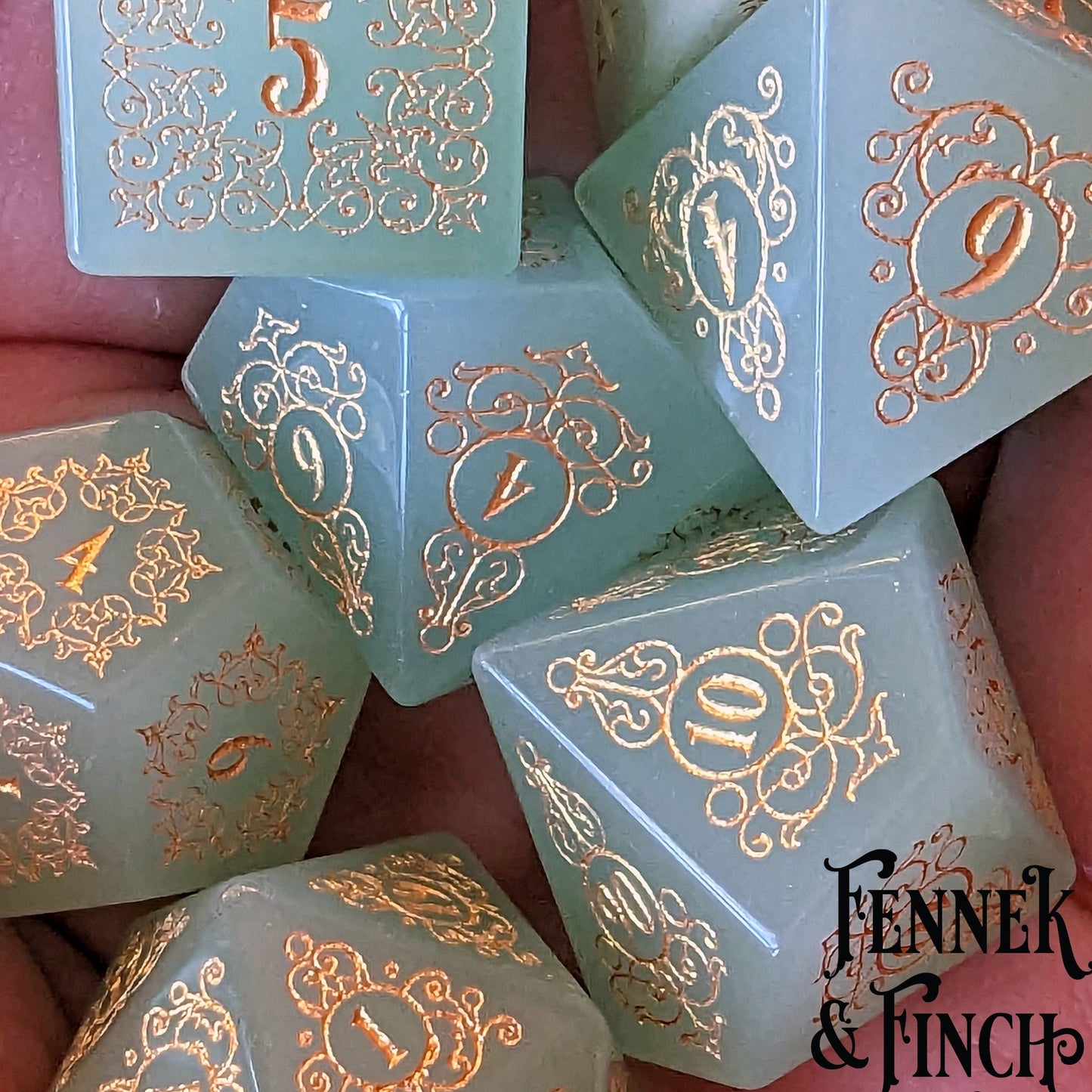 Milky green glass gemstone dice set with intricate floral and swirl designs, evoking a sense of magical invitation.