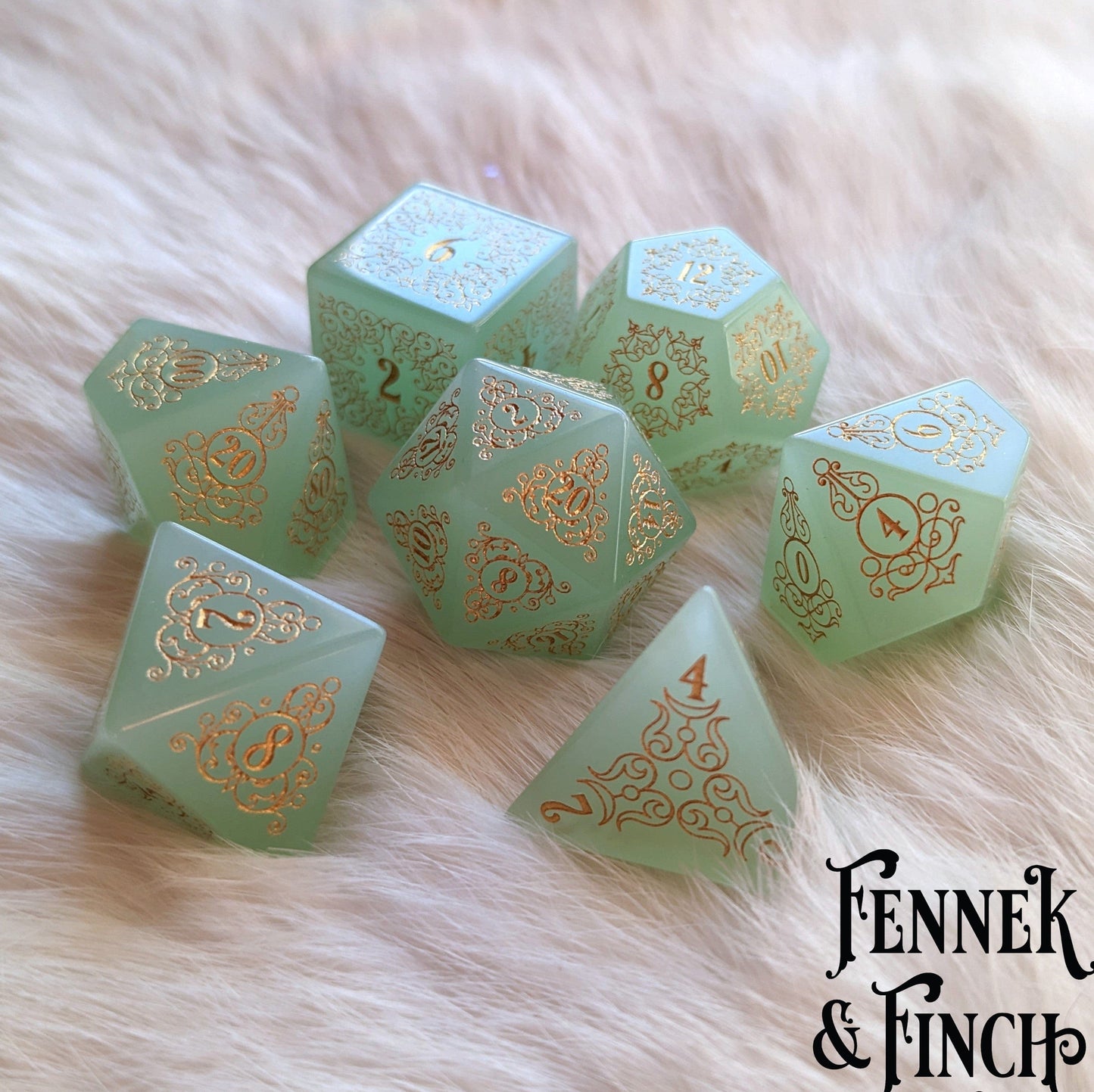 Garden Gate Milky Green Glass Gemstone Dice Set with floral and swirl designs on a soft fur background.