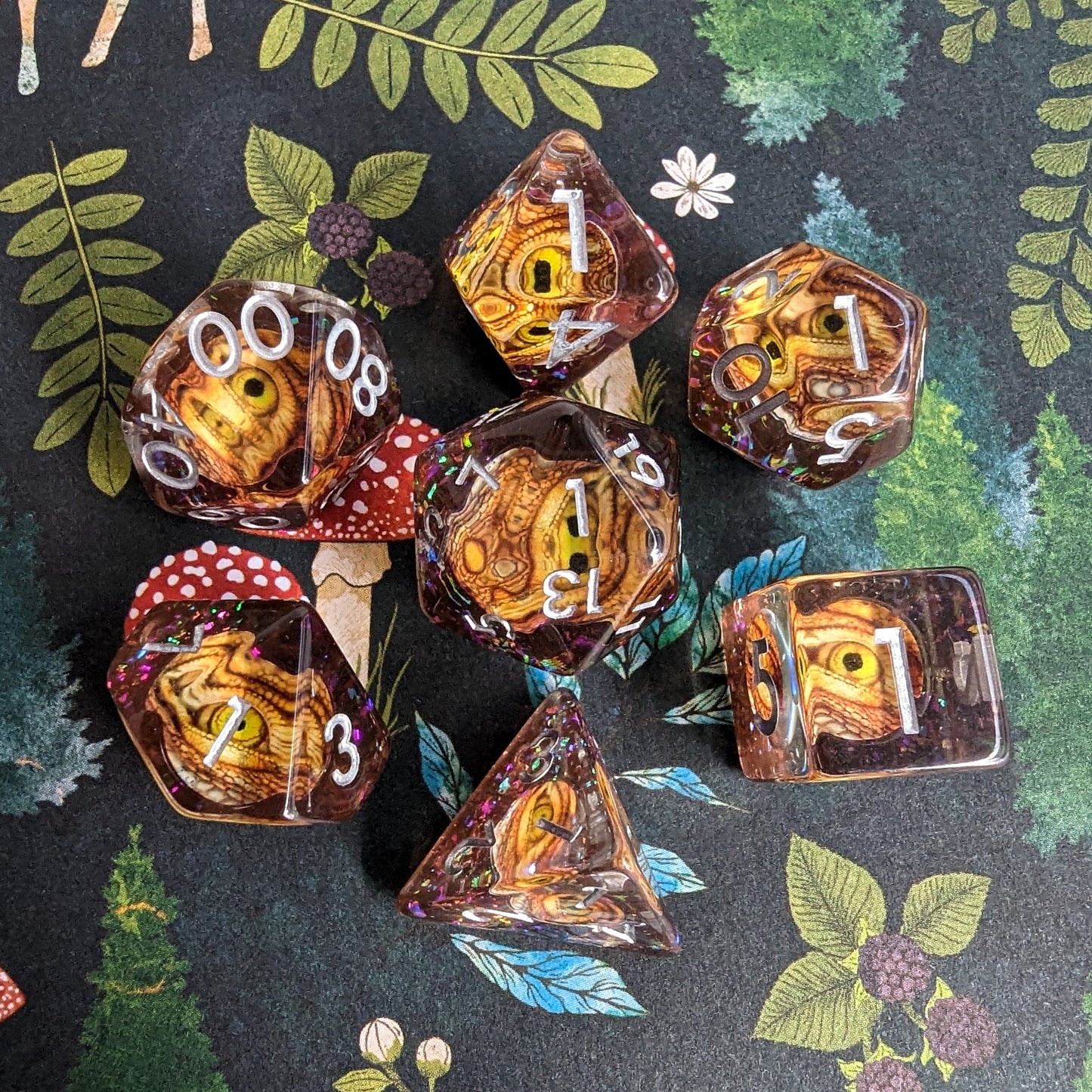 Golden Eye DnD Dice Set with detailed eye design, 7-piece polyhedral set for tabletop RPGs, displayed on a nature-themed background.