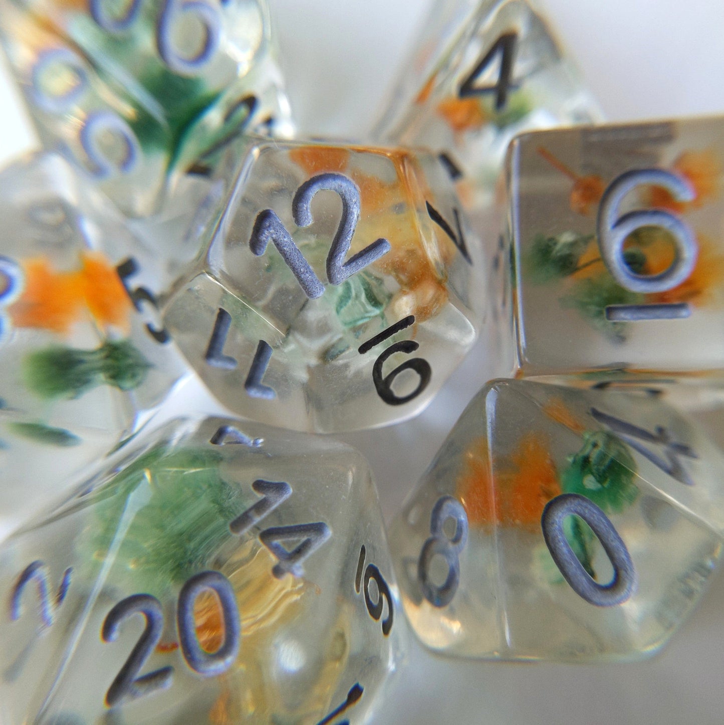 Green and orange flower dice set with real dried flowers inside, 7-piece polyhedral resin dice for tabletop RPGs like DnD.