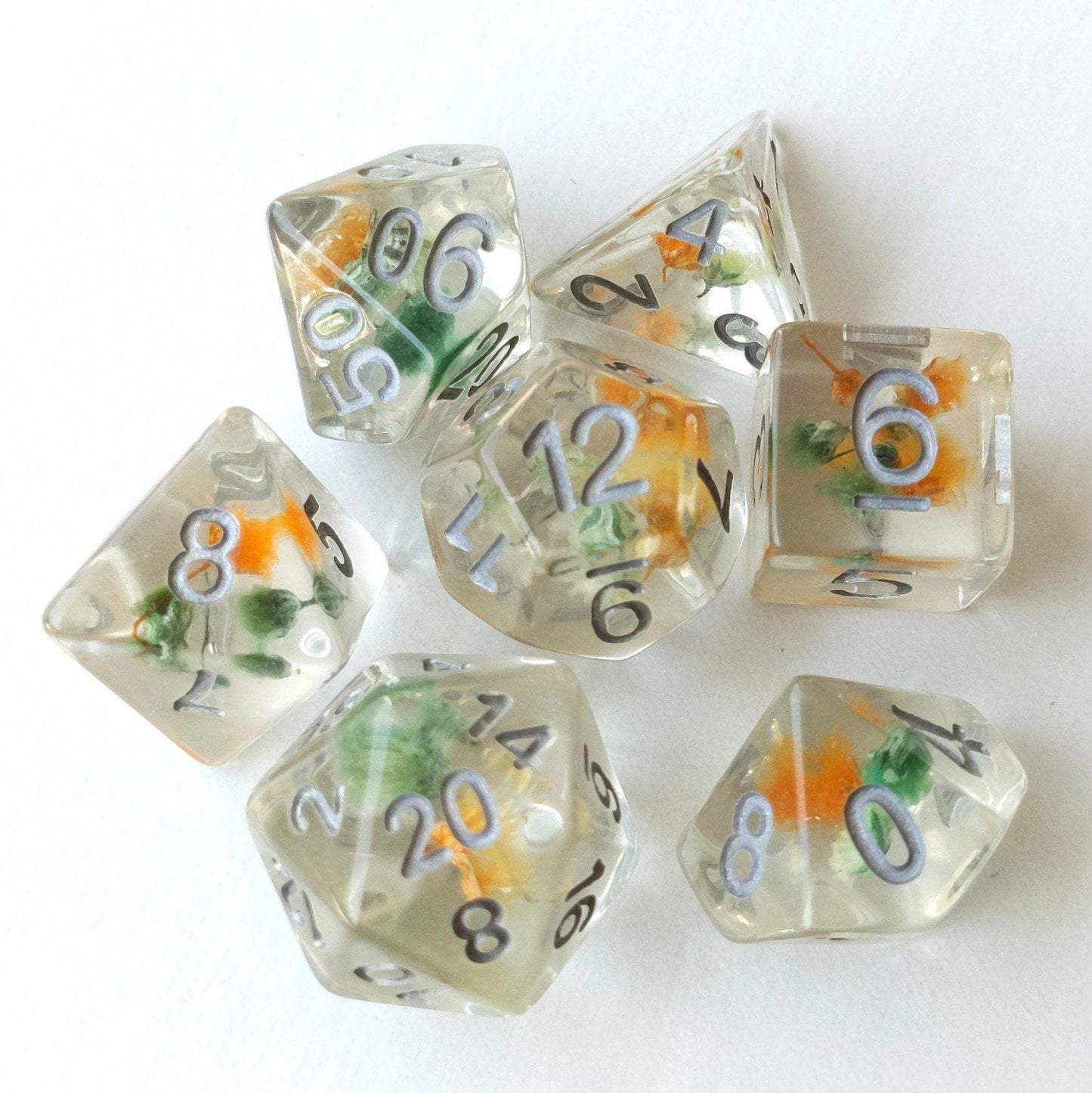 Green and orange flower dice set with real dried flowers, 7-piece polyhedral resin dice for tabletop games like Dungeons and Dragons.