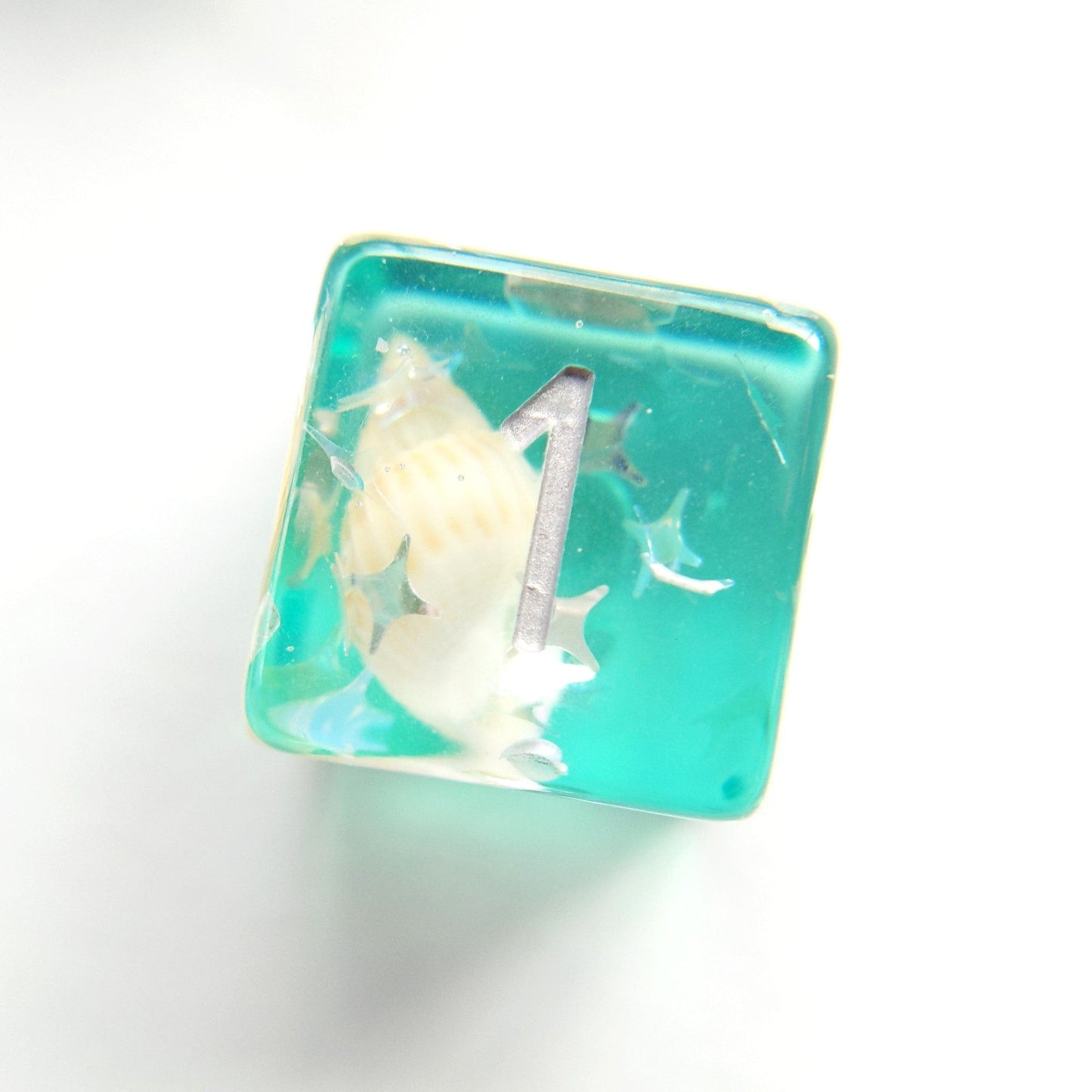 Green conch dice showing number one, featuring real seashell and star glitter in clear resin for tabletop games.