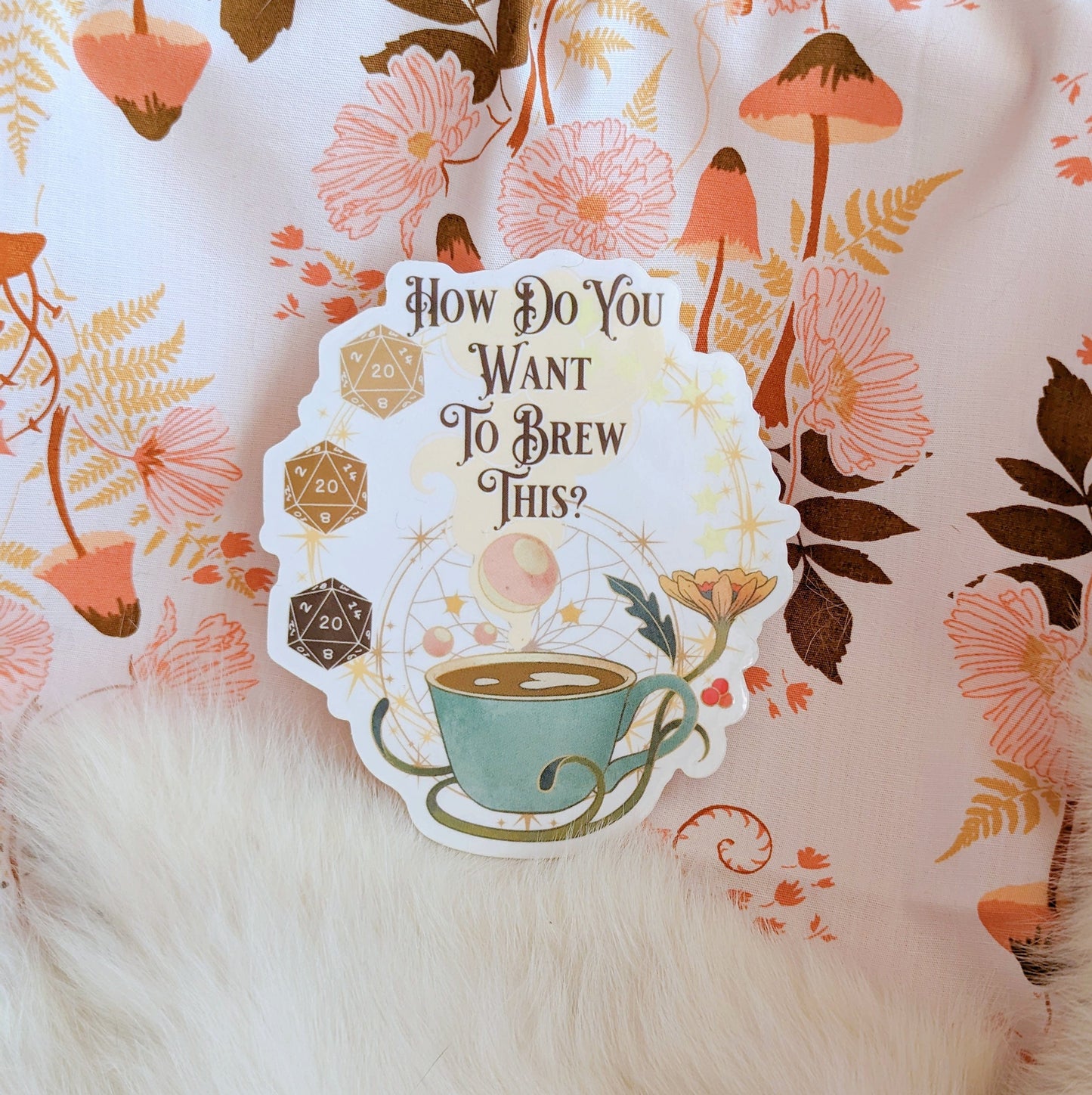 Dungeons and Dragons coffee-themed vinyl sticker featuring a cup and dice, surrounded by floral patterns on decorative fabric.