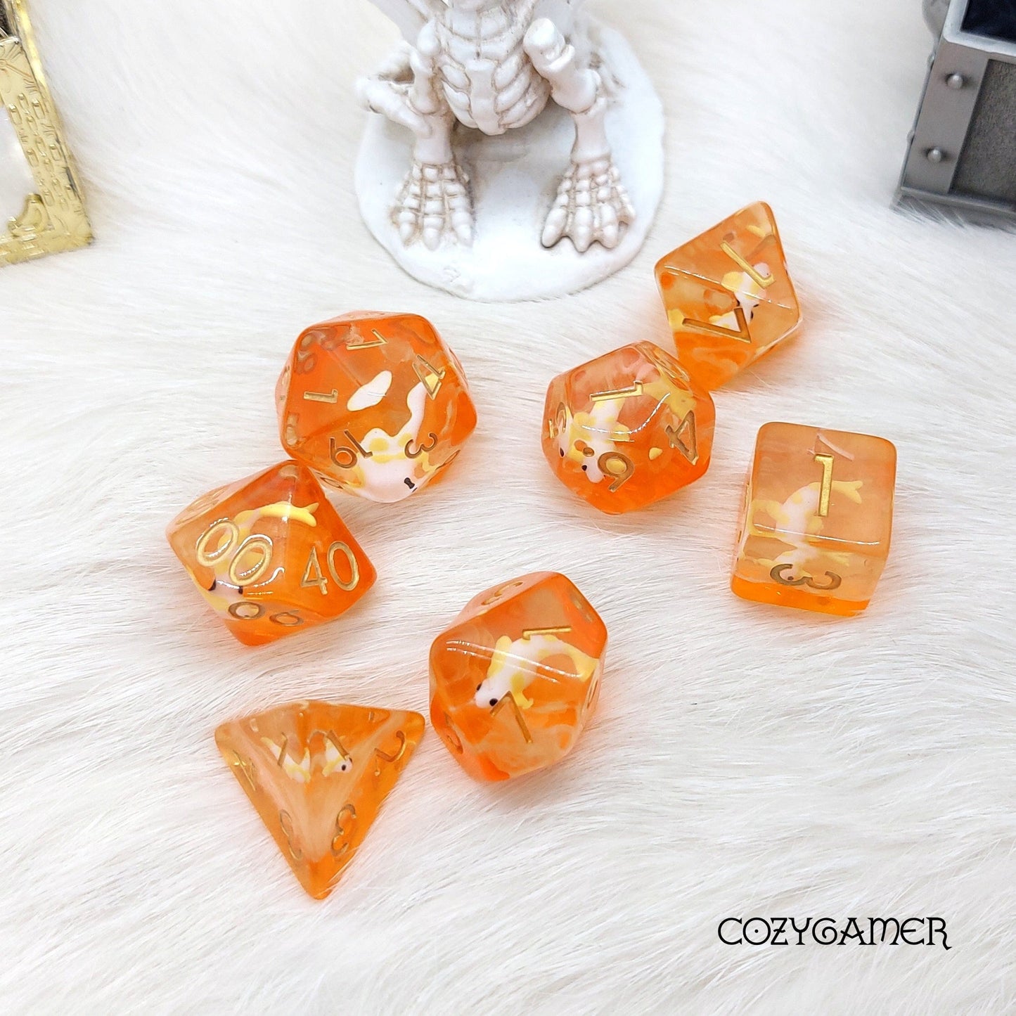 Orange translucent koi fish dice set for tabletop RPGs, featuring a 7-piece polyhedral collection on a white furry surface.