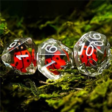 Ladybug themed Dungeons and Dragons dice set on moss, featuring resin insects inside clear polyhedral dice.
