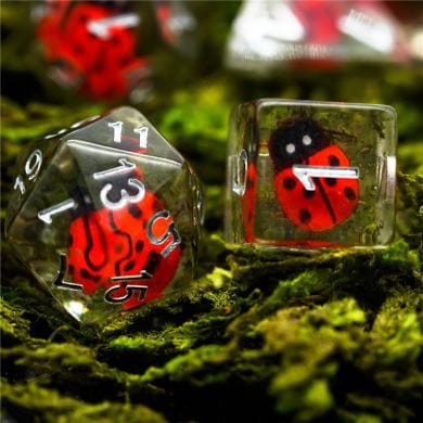 Ladybug dice set on moss, featuring insect-themed resin dice for Dungeons and Dragons and other tabletop RPGs.