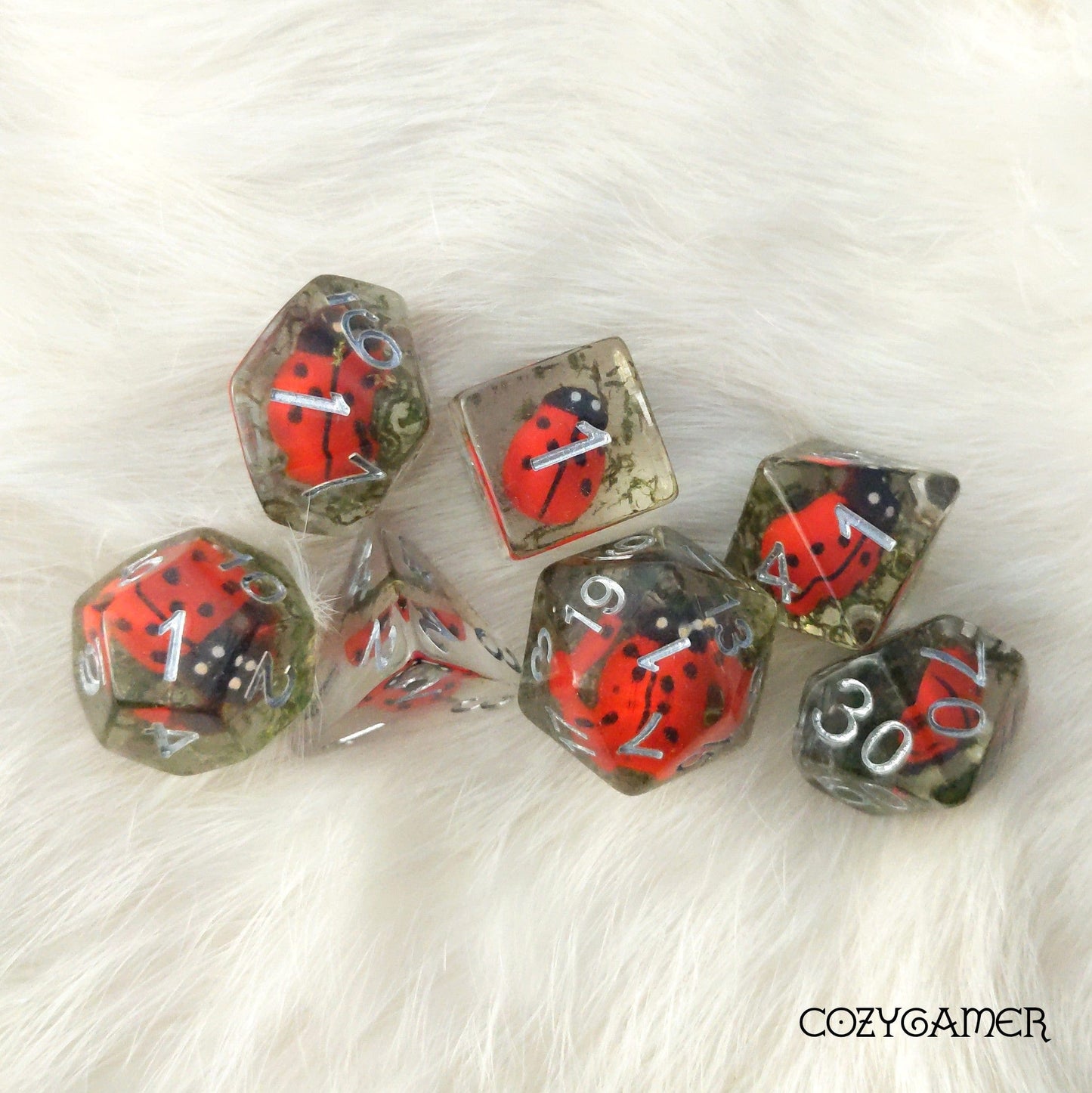 Ladybug-themed dice set with moss, perfect for Dungeons and Dragons. Features insects encased in resin. 7-piece TTRPG dice set.