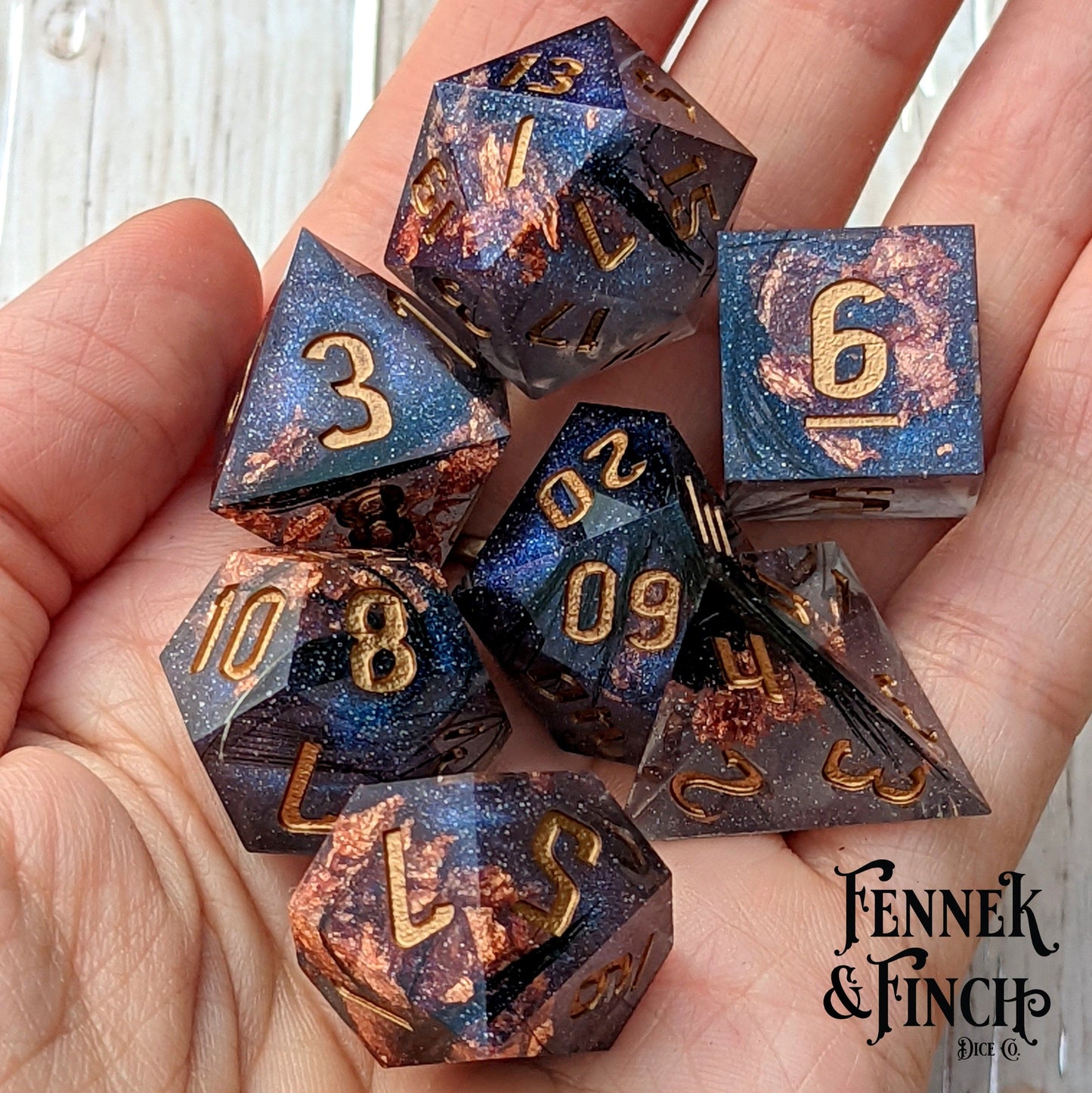 Magic Feather Dice Set with black feathers, copper foil, and glitter in hand, Dungeons and Dragons 7-piece resin dice set.