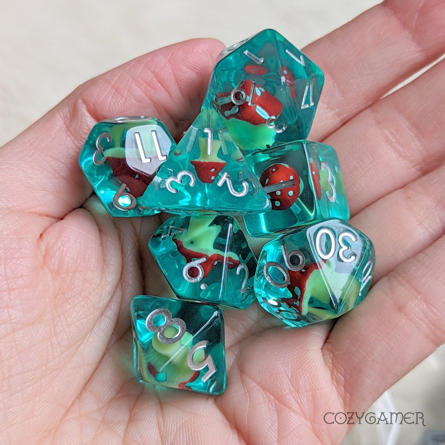 Blue resin Mushroom Tea Dice Set with tiny amanita designs for Dungeons and Dragons tabletop games, hand-held for display.