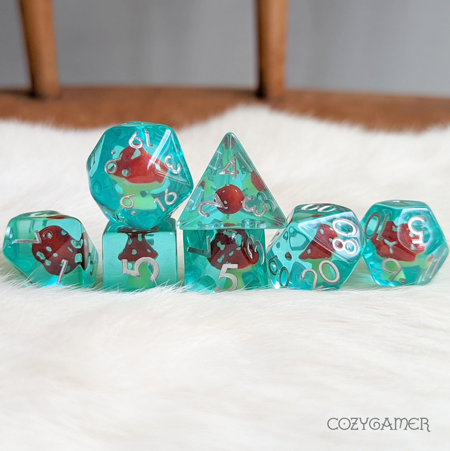 Blue resin polyhedral dice set with tiny Amanita mushrooms for tabletop games like Dungeons and Dragons.